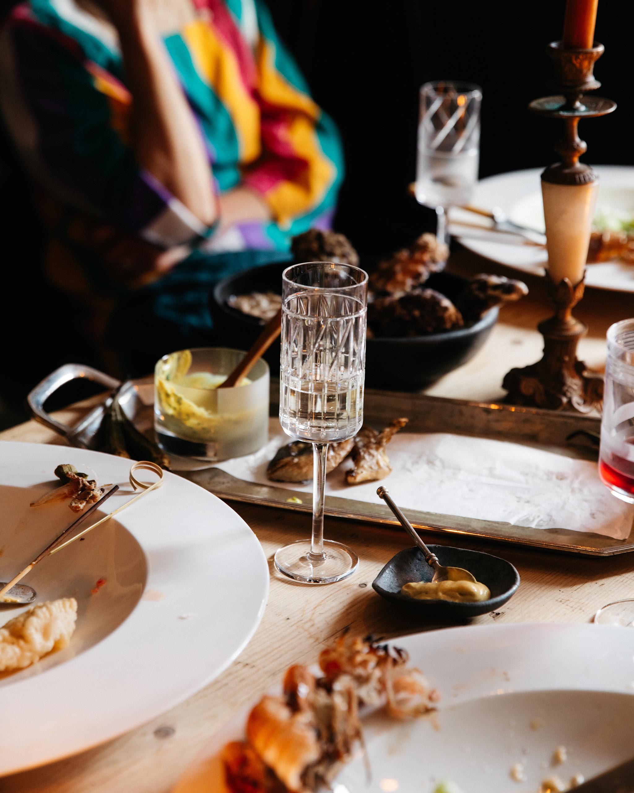 Hand-cut Irish crystal Thorn Collection champagne flute filled with sparkling wine, styled in a festive dinner scene with partially eaten food on the table.