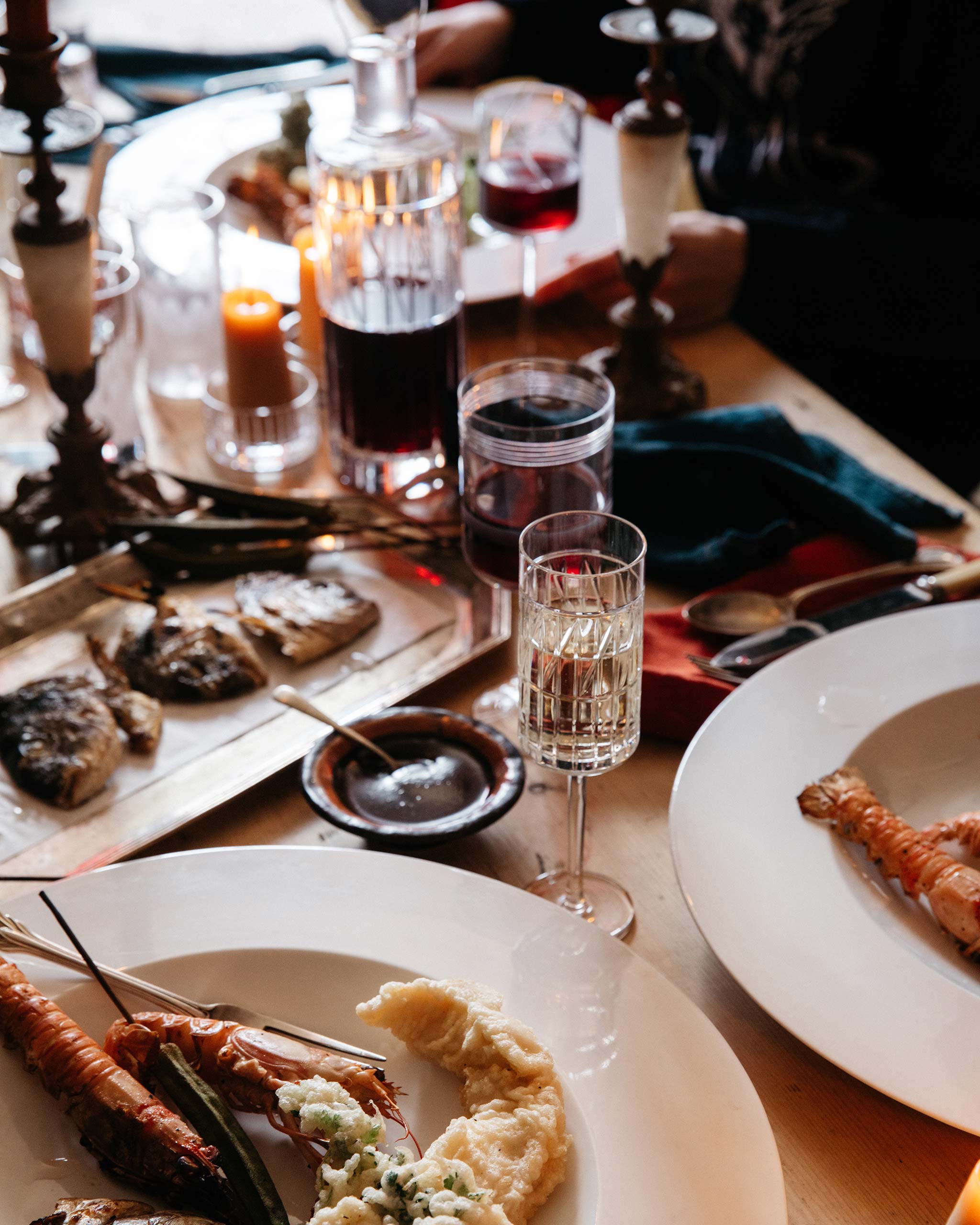 Thorn Collection hand-cut Irish crystal champagne flute filled with sparkling wine, paired with a red wine glass, styled on a festive table with food.