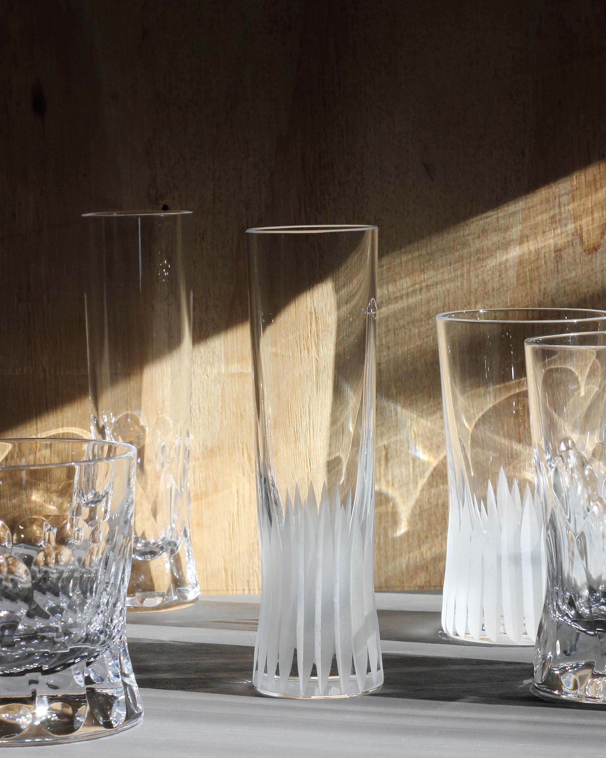 Assortments of hand-cut Irish crystal glasses with deep angular cuts inspired by ploughed soil on a warm ambient background