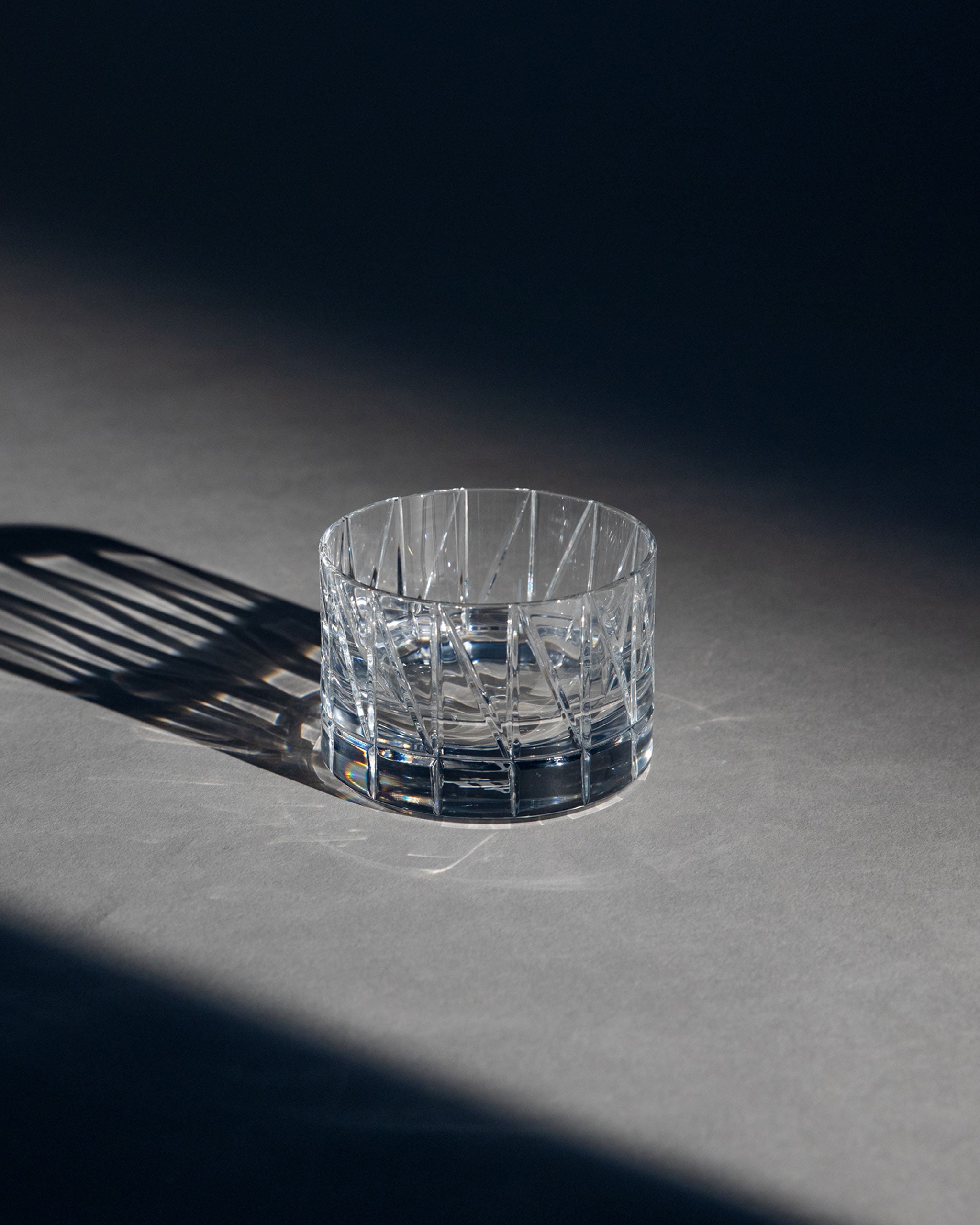 Cut crystal low glass with bold thorn-inspired pattern, ideal for whiskey, wine, or cocktails against an ambient background