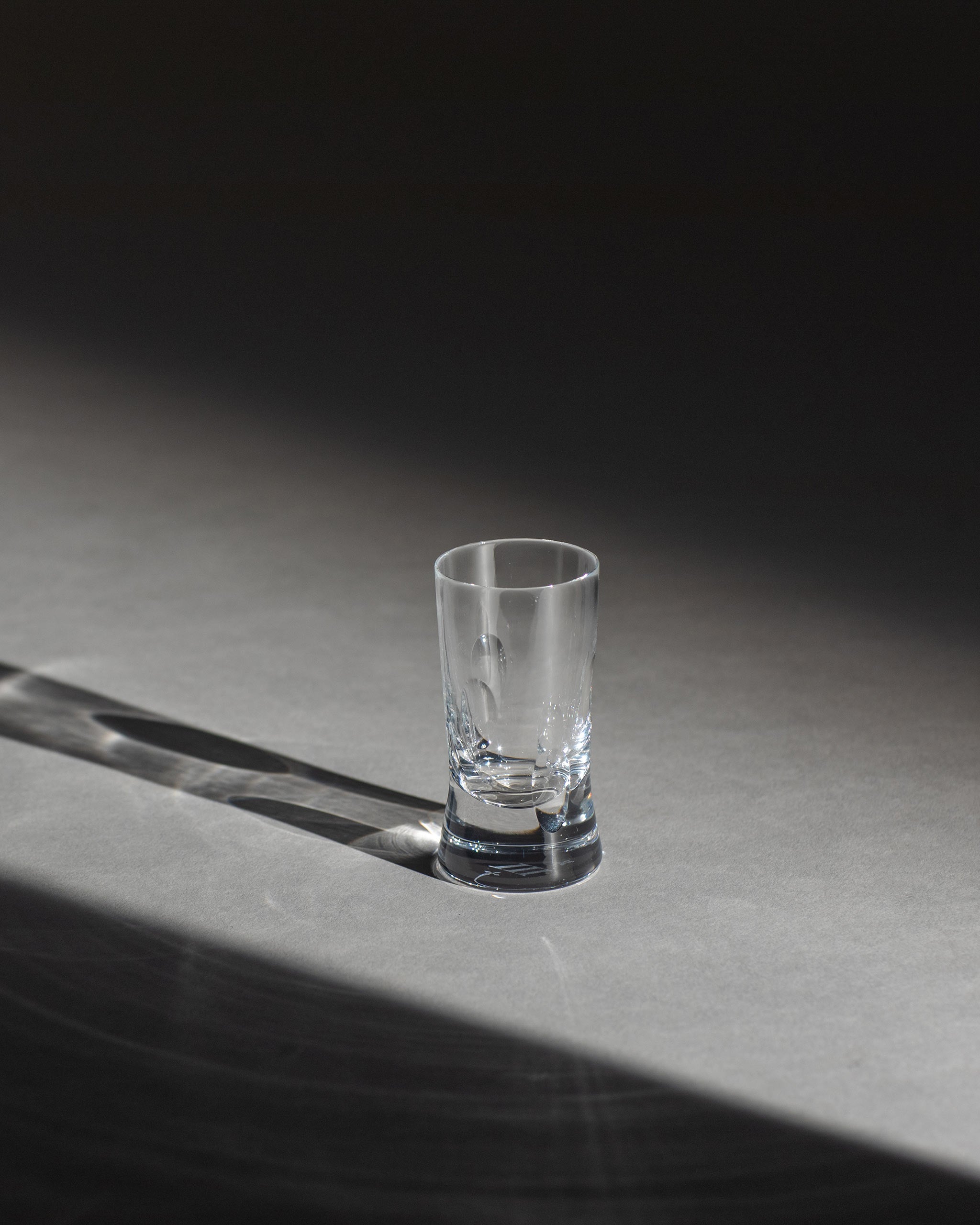 Polished hand-cut Irish crystal shot glass with softly polished and sandblasted dew-cut detailing on an ambient background