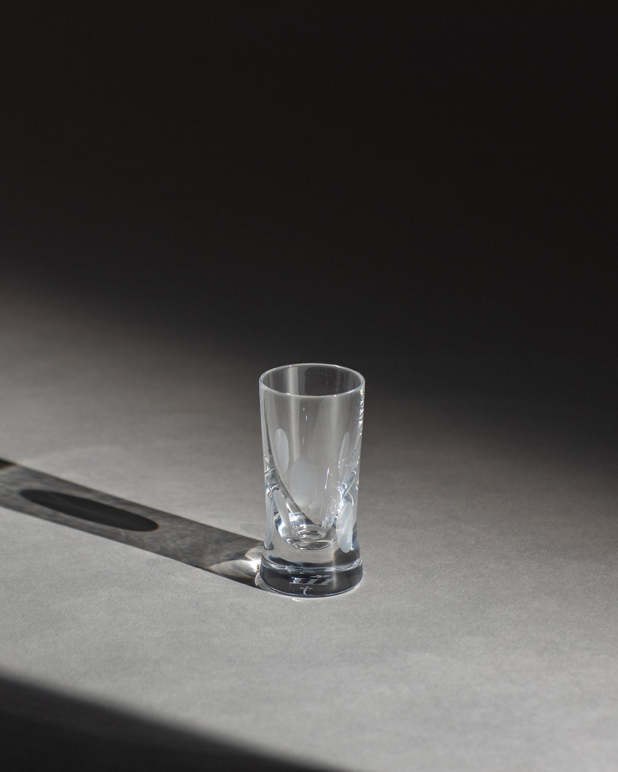 Unpolished hand-cut Irish crystal shot glass with softly polished and sandblasted dew-cut detailing on an ambient background