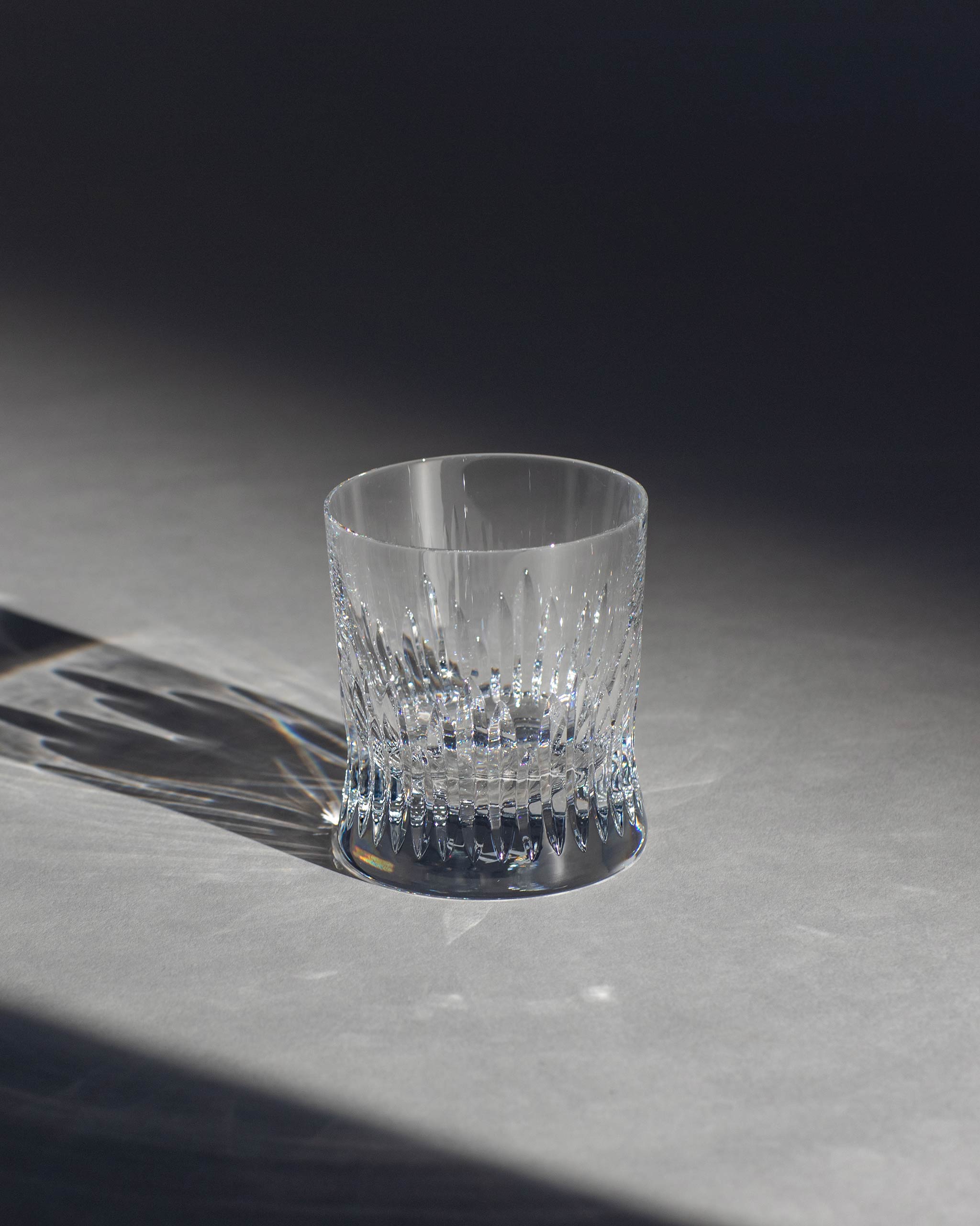Polished hand-cut Irish crystal whiskey glass with deep angular cuts inspired by ploughed soil on an ambient background