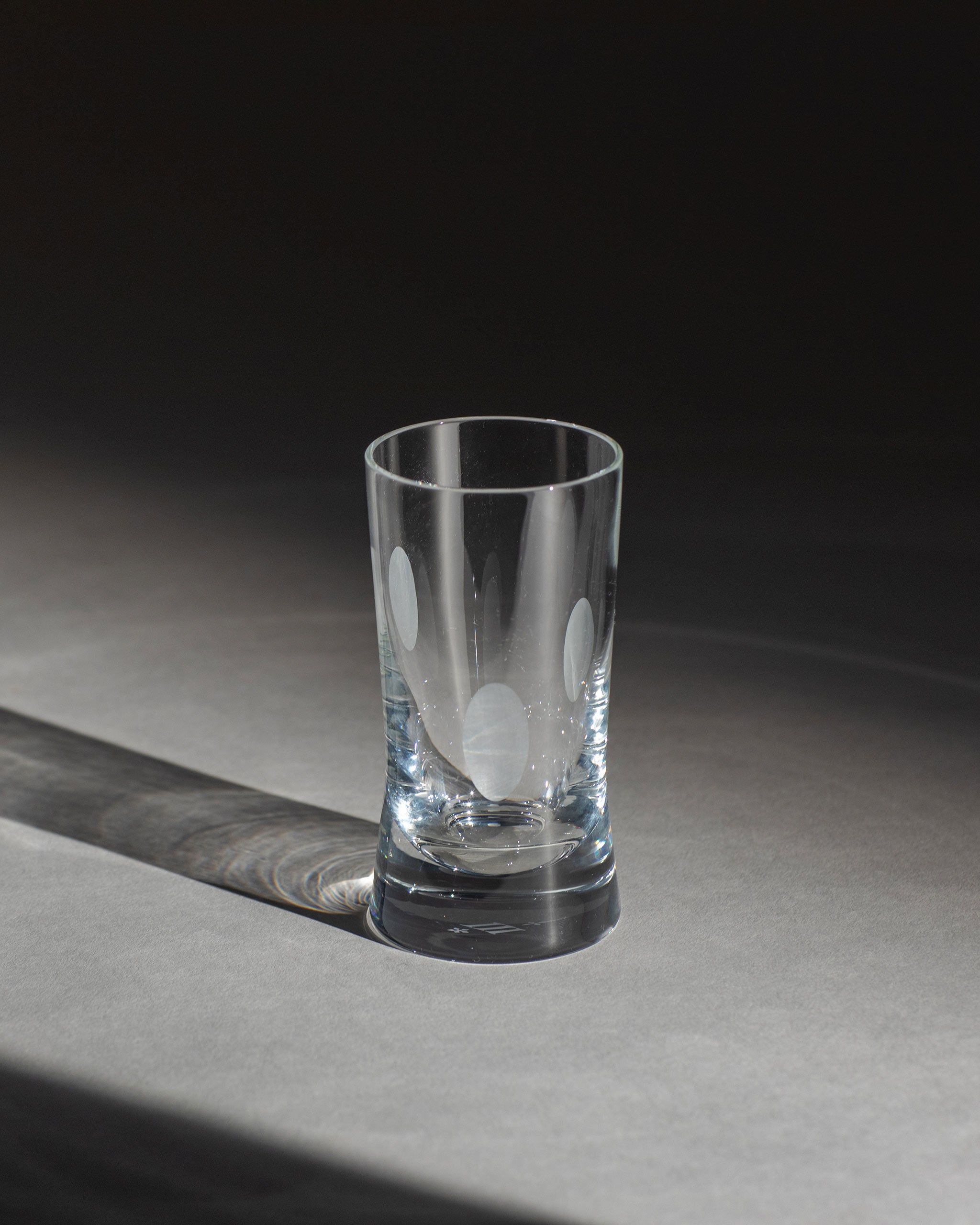 Unpolished hand-cut Irish crystal white wine or water glass with softly polished and sandblasted dew-cut detailing on an ambient background