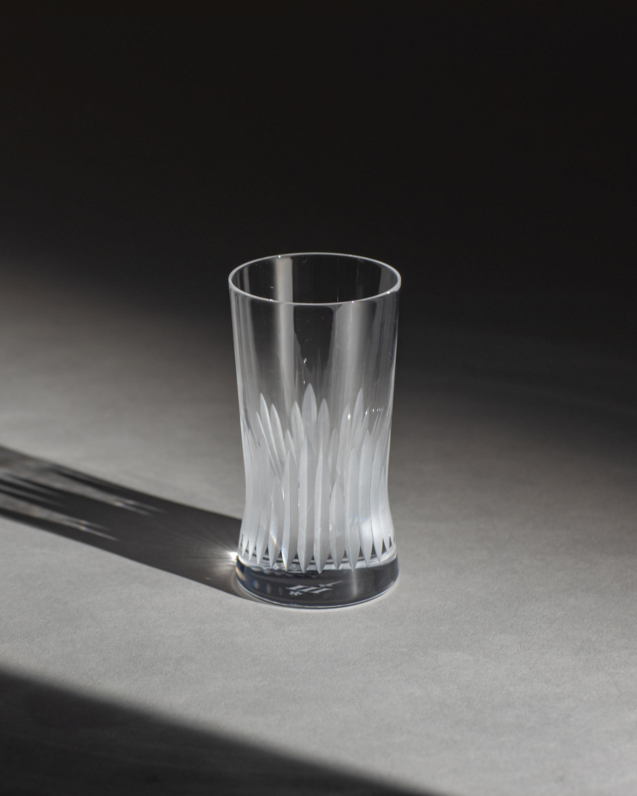 Unpolished hand-cut Irish crystal red wine glass with deep angular cuts inspired by ploughed soil on an ambient background