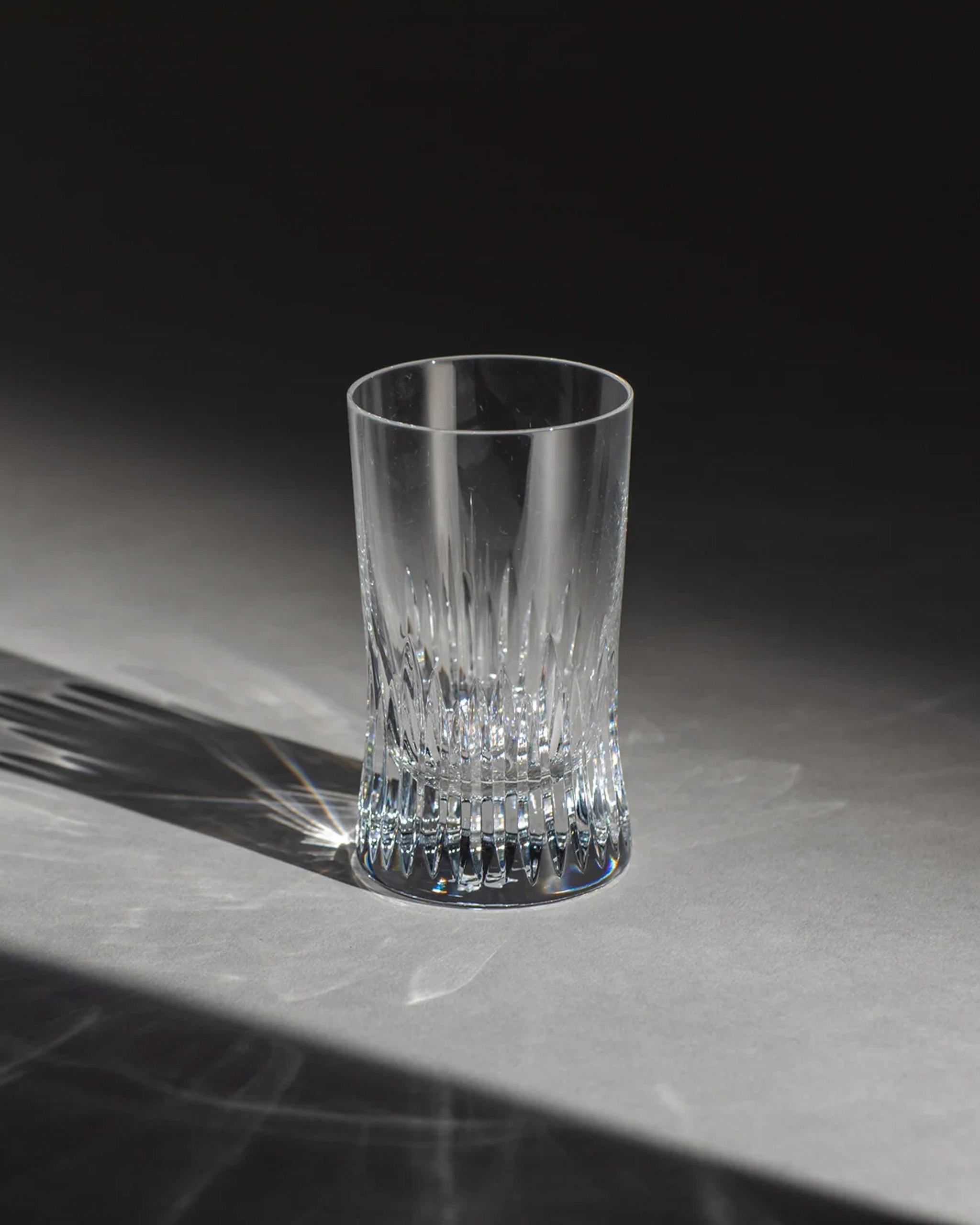 Polished hand-cut Irish crystal rocks tumbler glass with deep angular cuts inspired by ploughed soil on an ambient background