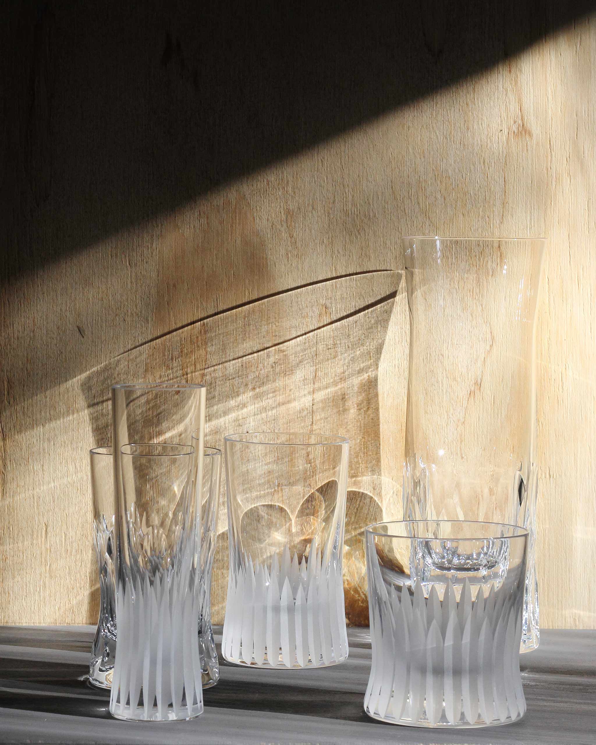 Array of hand-cut Irish crystal glasses with deep angular cuts on a warm ambient background
