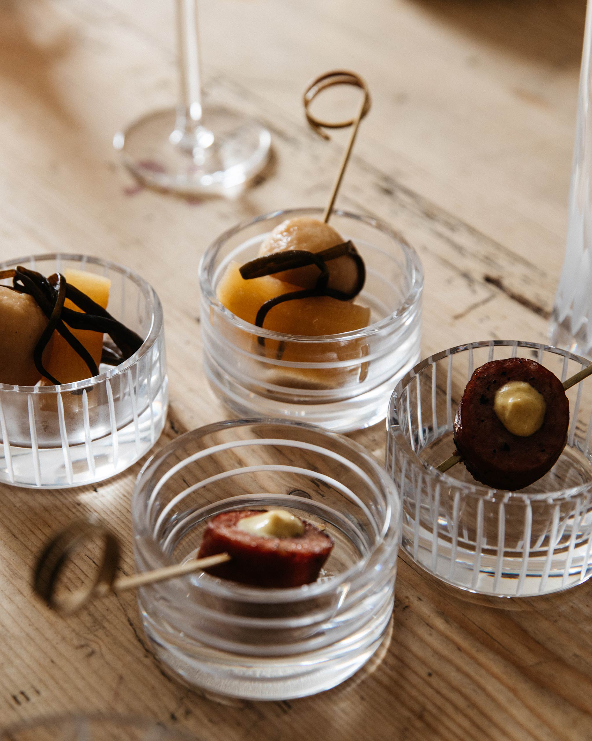 Row Collection crystal votives holding artisanal festive nibbles, styled on a warm, celebratory table to showcase texture and luminous quality.