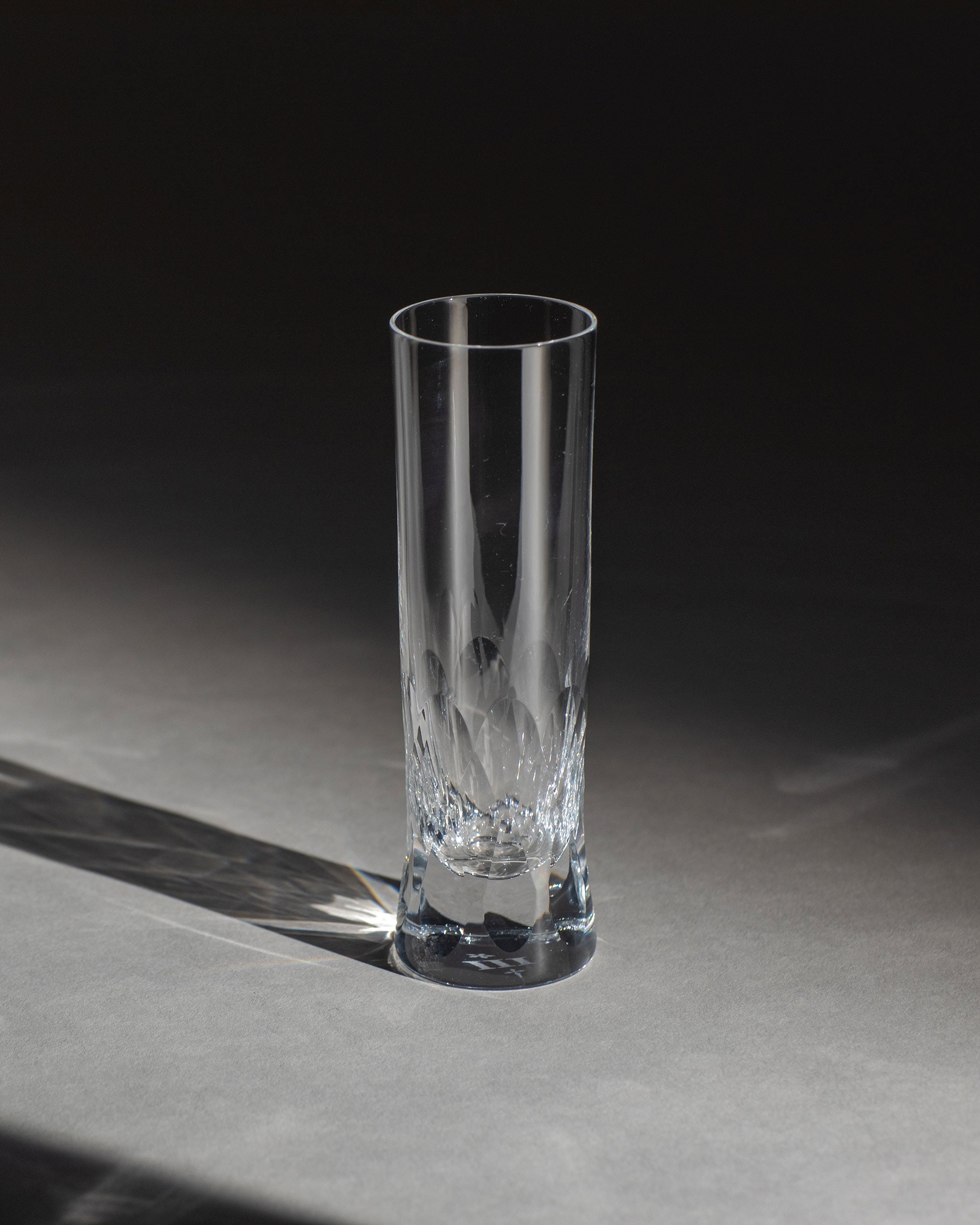 Polished Irish hand-blown cut crystal champagne flute with large cut pattern detailing on an ambient background