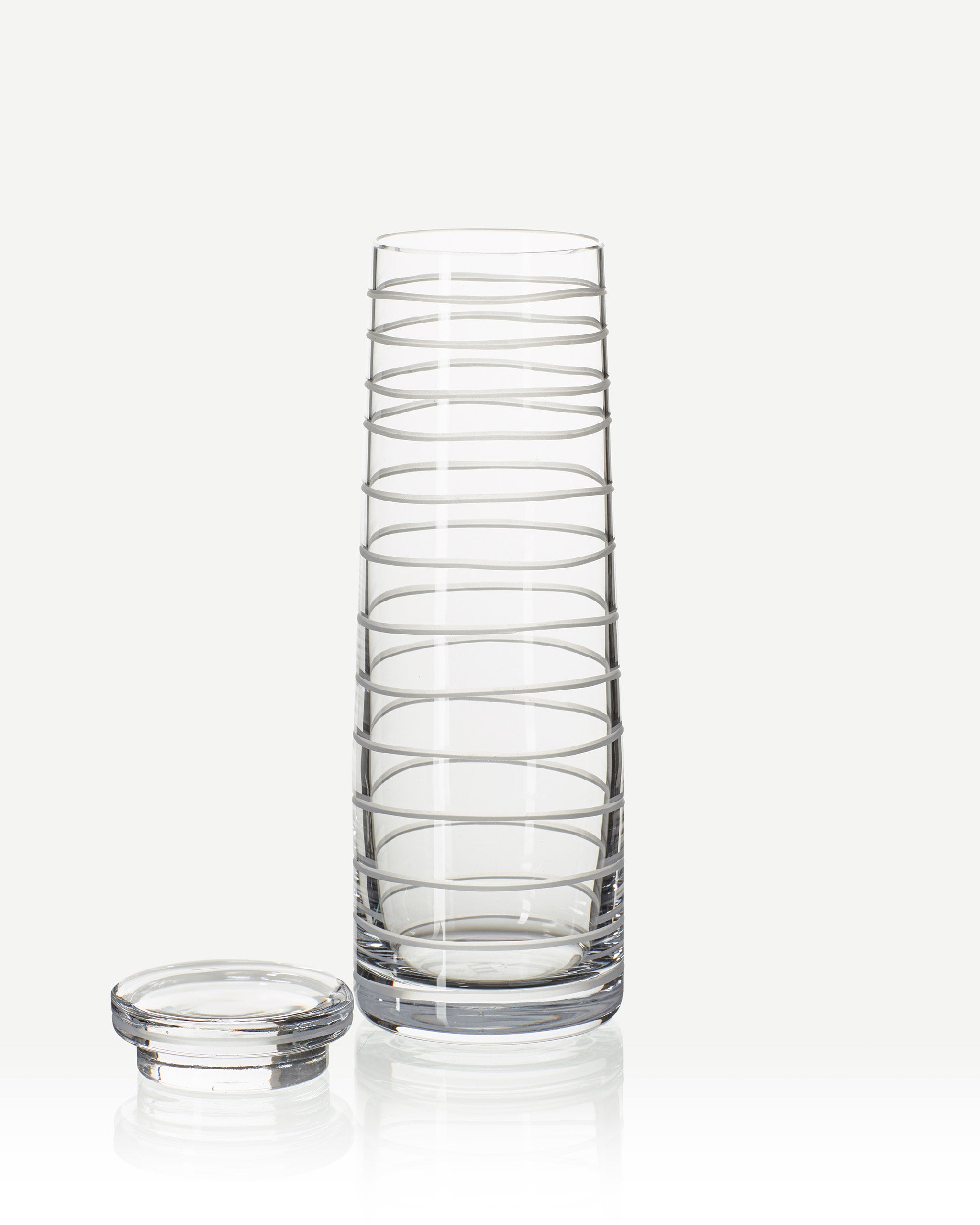 Handcrafted crystal decanter with a continuous loop pattern of horizontal cuts, echoing natural rhythm and movement, designed for sake, wine, or cocktails on a white background
