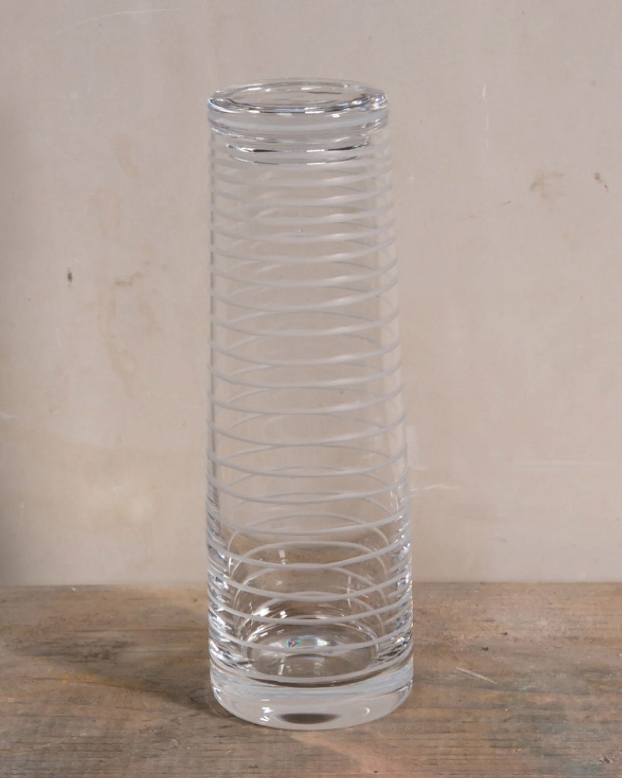 Handcrafted crystal decanter with a continuous loop pattern of horizontal cuts, echoing natural rhythm and movement, designed for sake, wine, or cocktails on a natural background