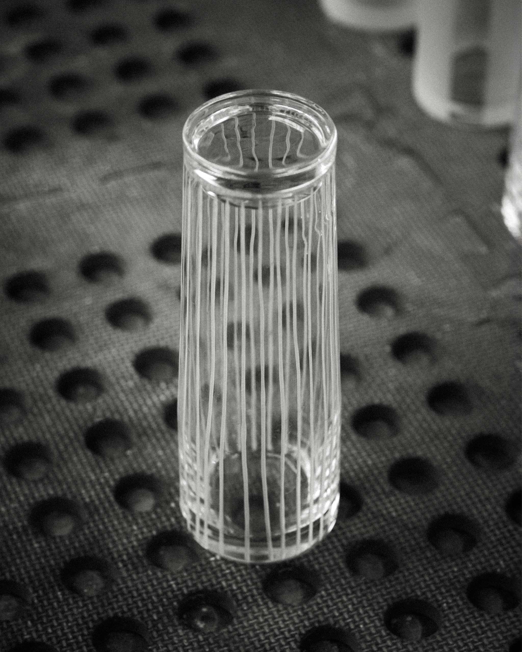 Hand-cut Irish crystal decanter with structured vertical cuts and broad base on a dark mat