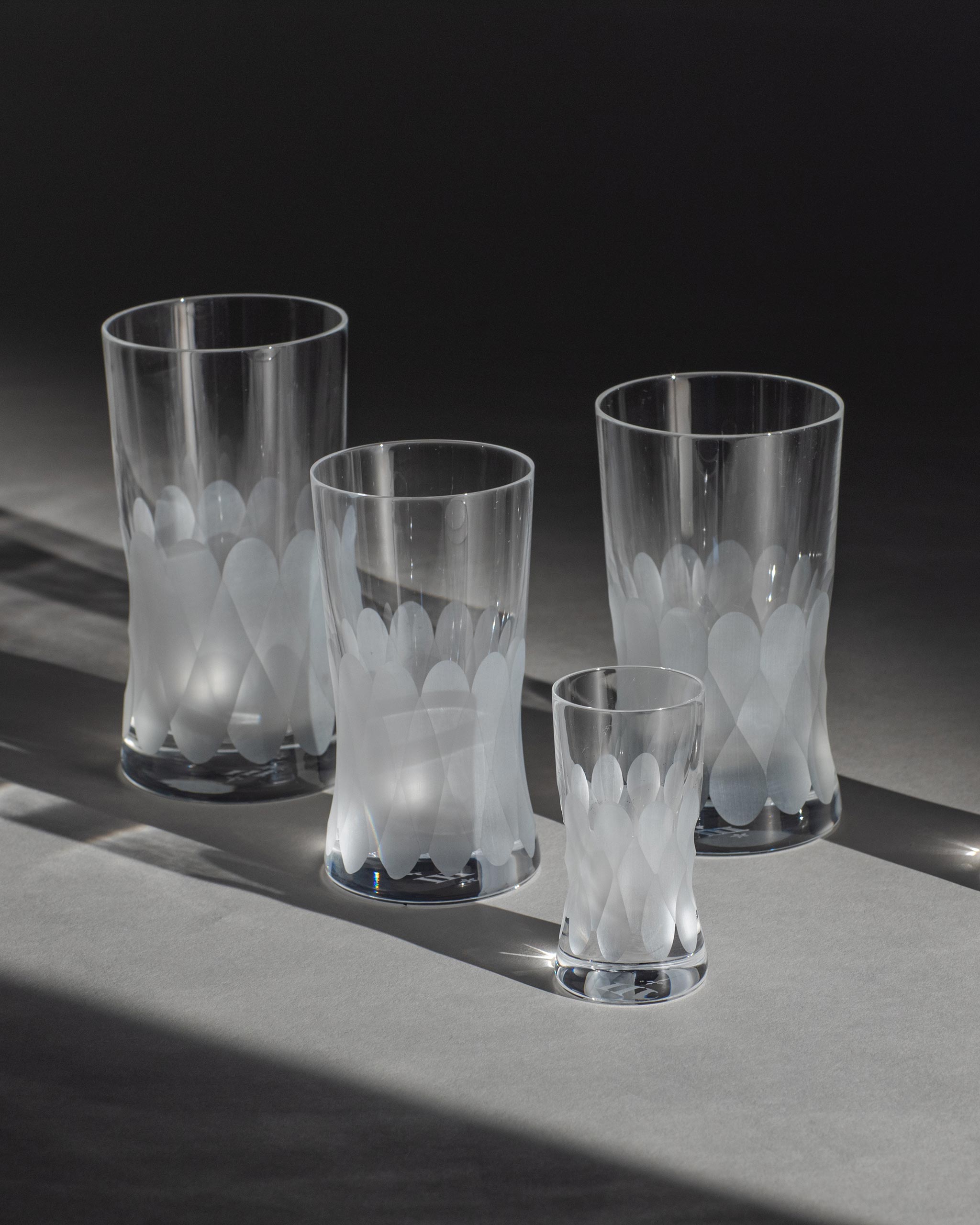 Unpolished Irish hand-blown crystal glasses, with interlocking cut patterns on an ambient background