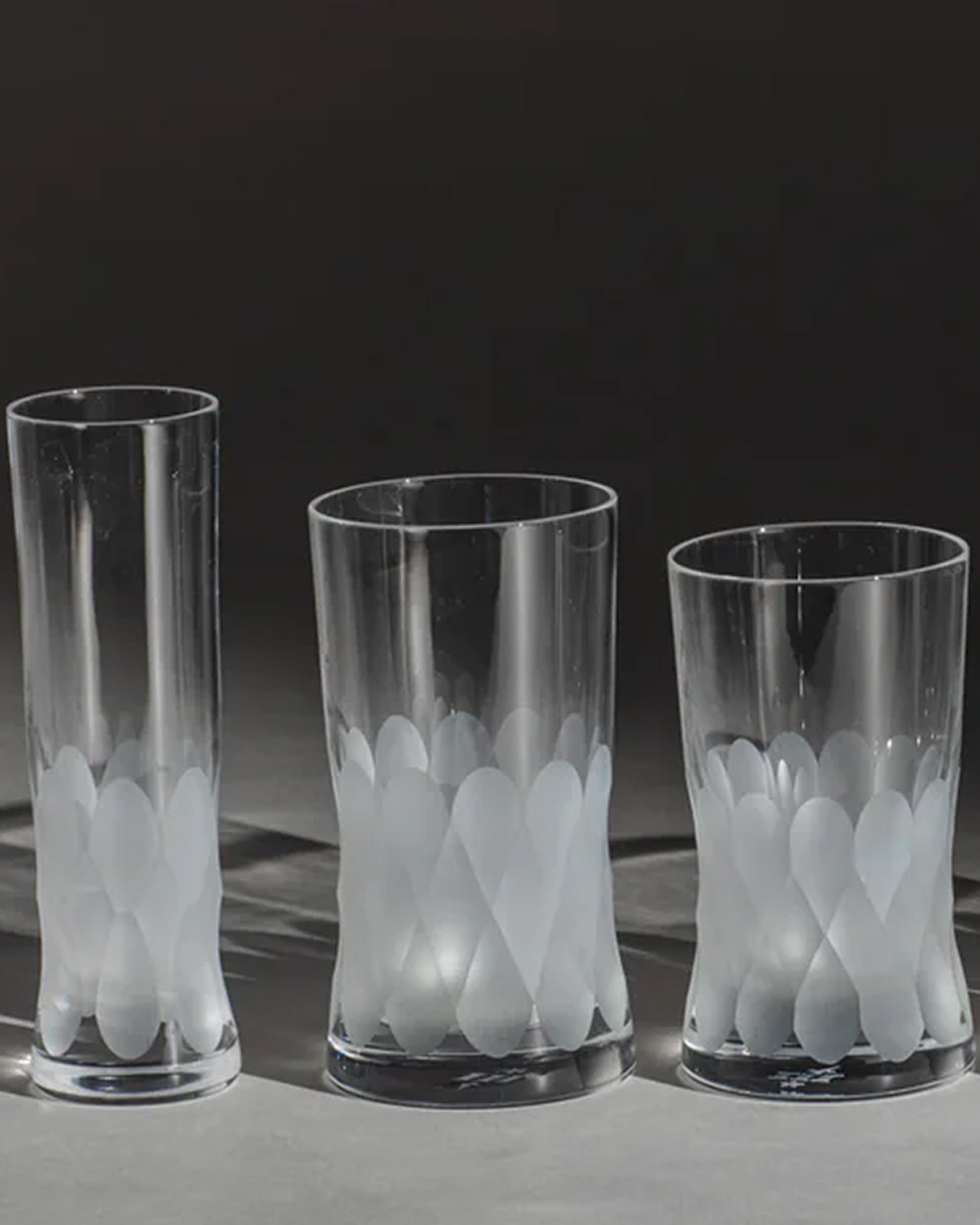 Trio of unpolished Irish hand-blown crystal glasses, with interlocking cut patterns on an ambient background