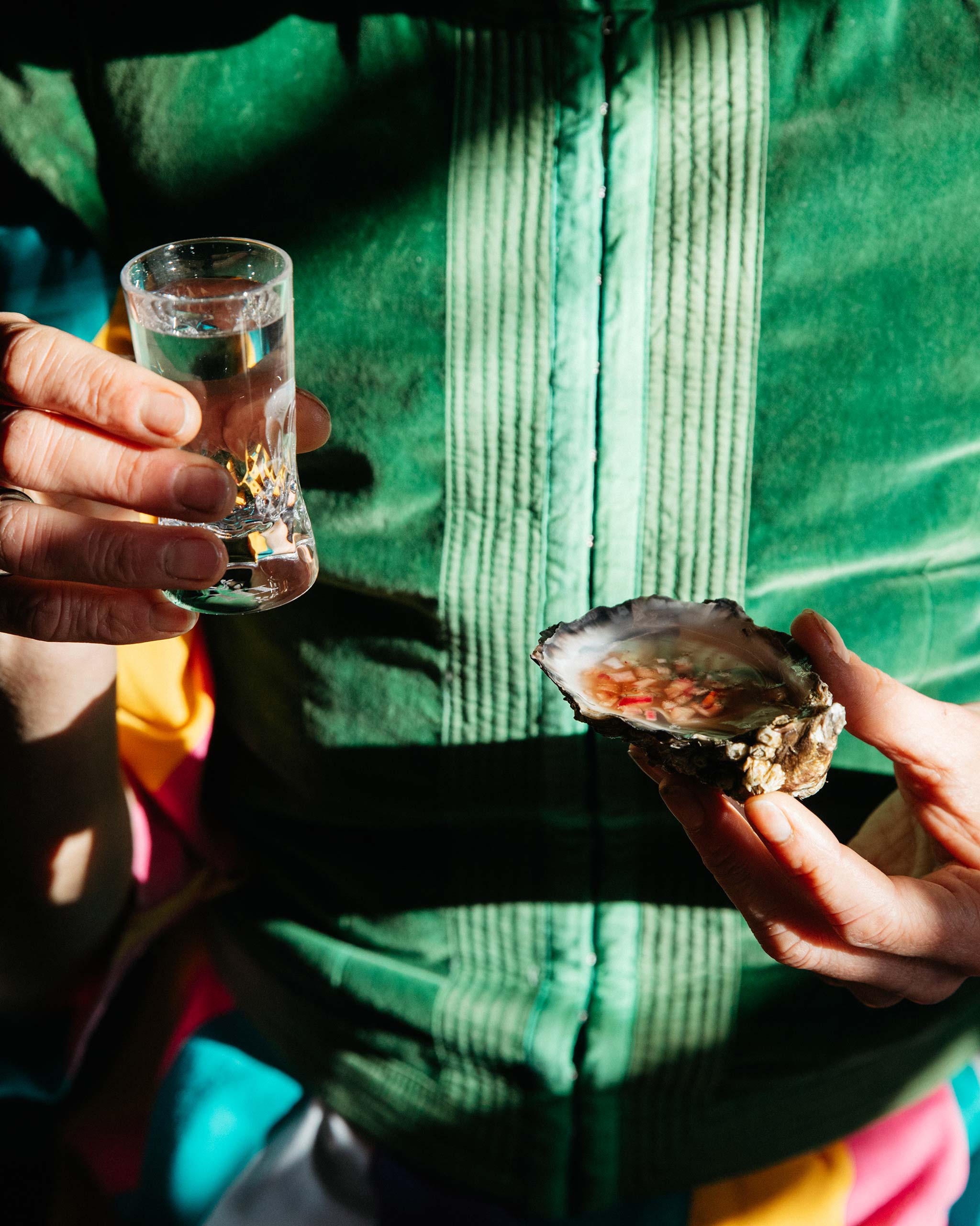 Lifestyle image of a person holding an oyster in one hand and an Irish hand-blown cut crystal shot glass in the other