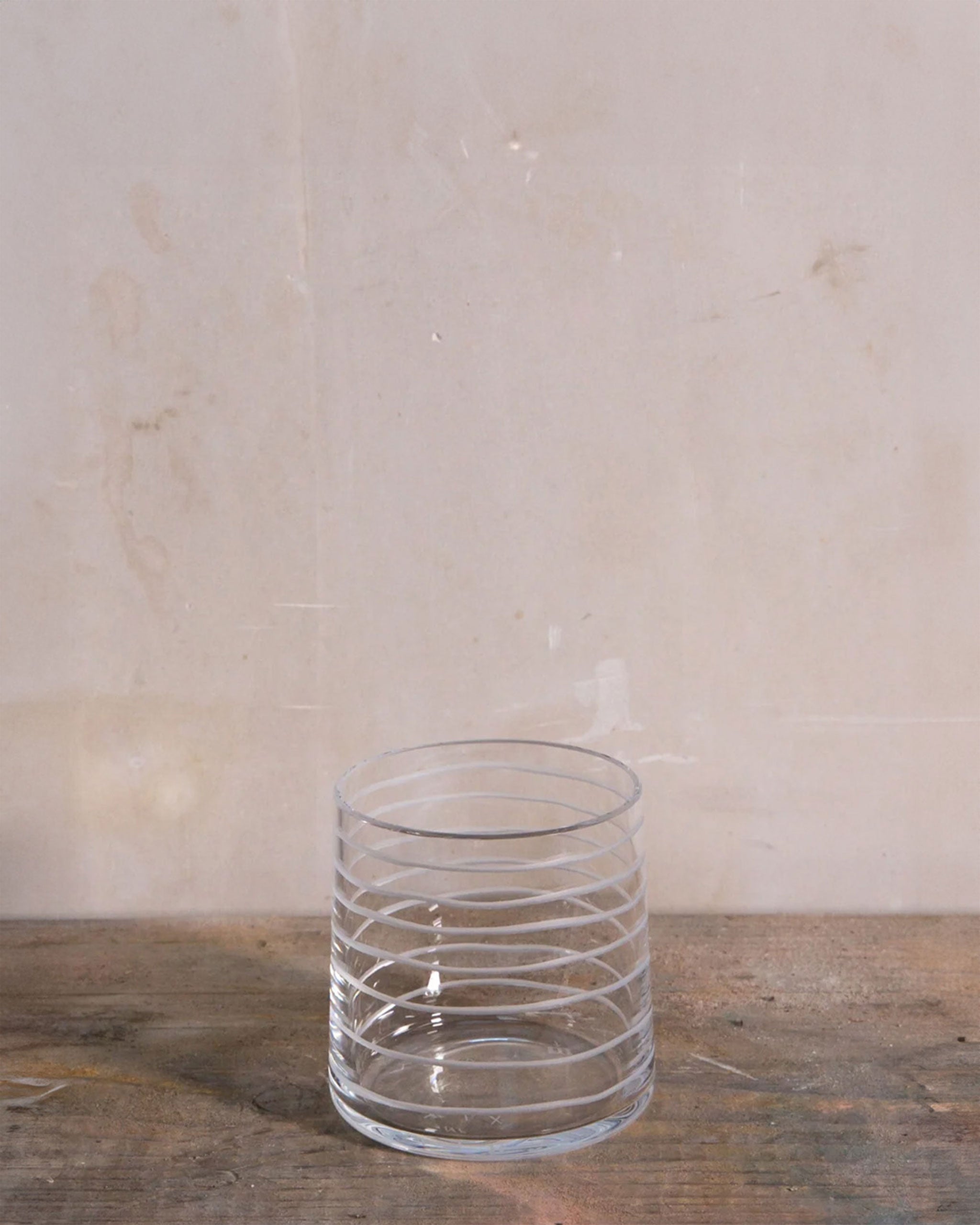 Slanted crystal tumbler from the Loop Collection featuring fine horizontal cuts in a spiral rhythm, combining contemporary design with artisanal craftsmanship.