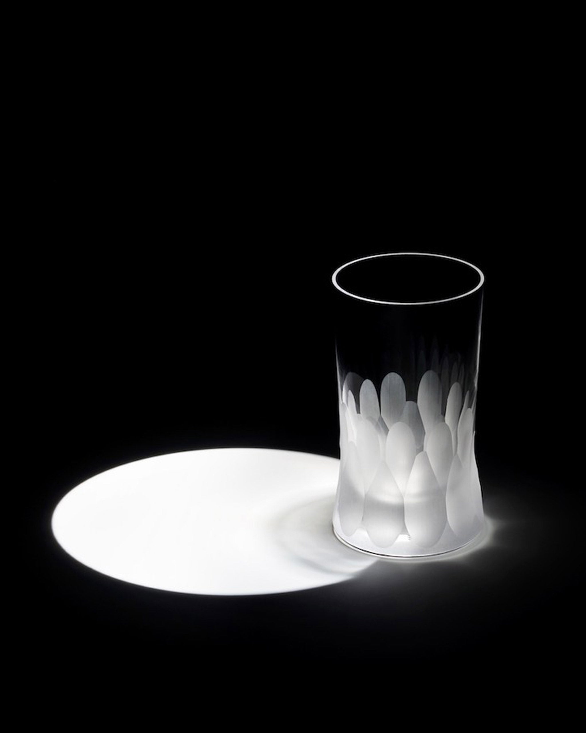 Unpolished Irish hand-blown cut crystal wine or water glass lit to highlight the large cut pattern detailing on an ambient background
