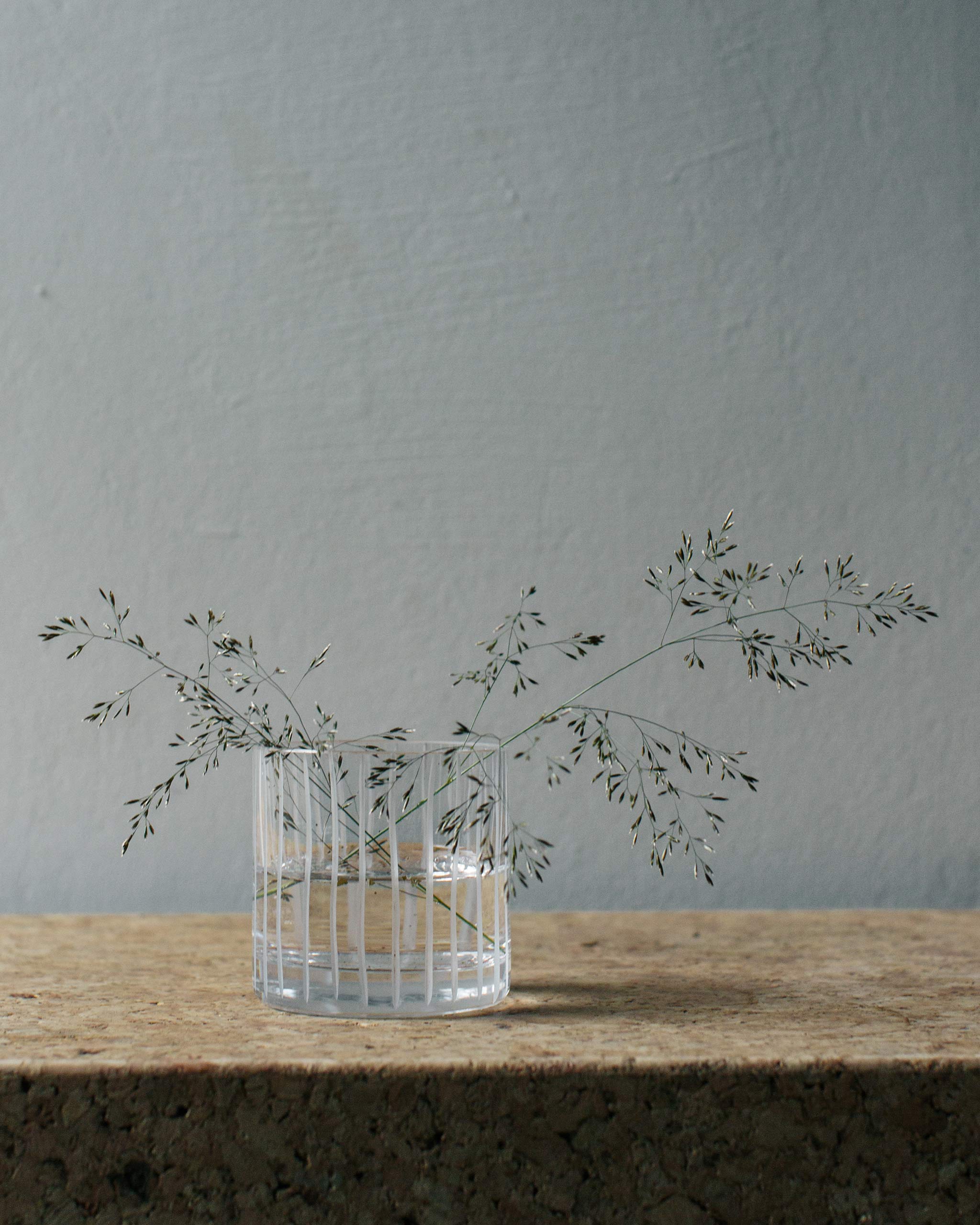 Row Collection straight hand-cut Irish crystal tumbler filled with water and a soft plant, styled on a natural lifestyle background to highlight form and texture.