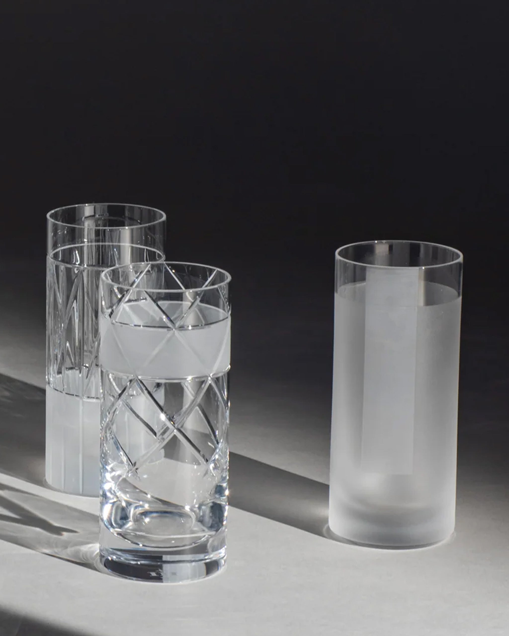 Selection of tall hand-crafted long crystal highball glass with frosted geometric design on an ambient background