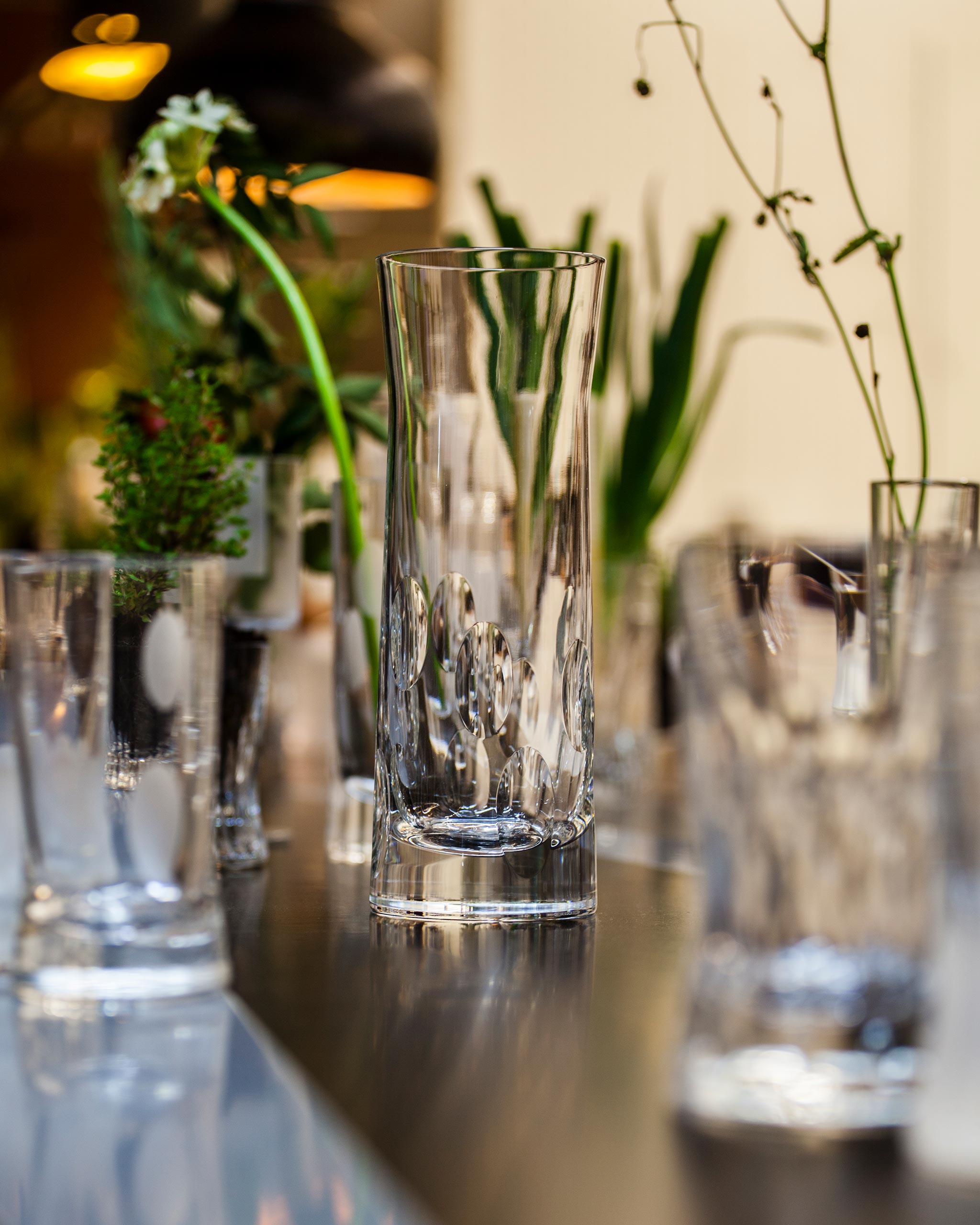 Lifestyle image of a table on which there sits a polished Irish hand-blown crystal carafe alongside a variety of other glassware and foliage