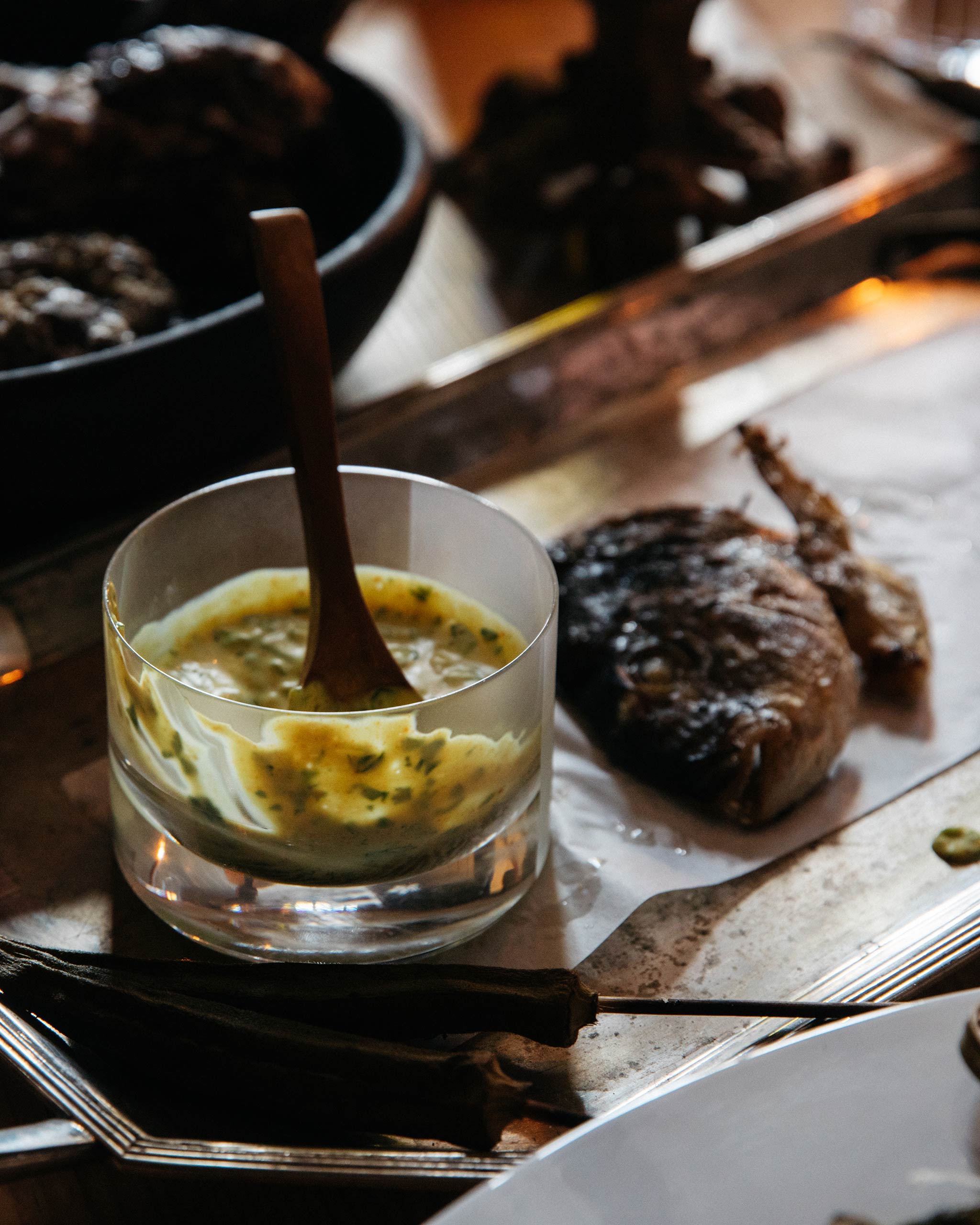 Crystal low drink glass used for sauce in an elegant table setting with cooked fish and silver spoon, styled dining scene.