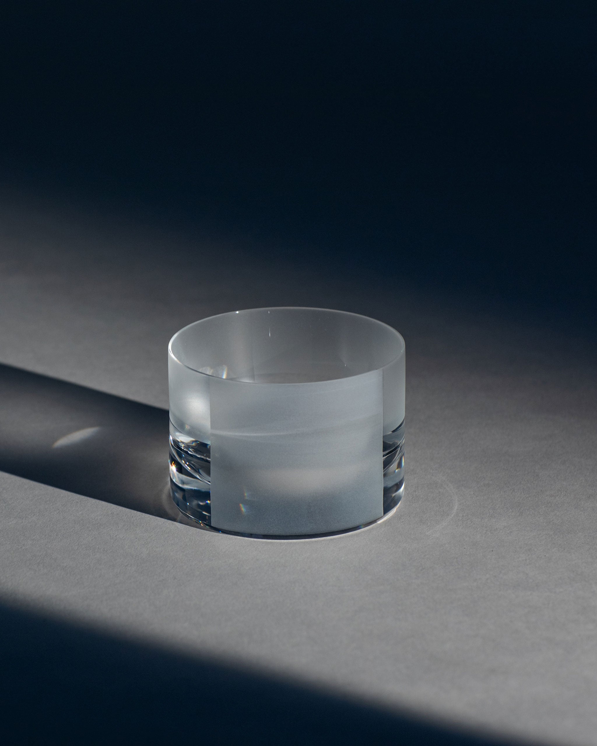 Low crystal tumbler with geometric sandblasted panels and a frosted texture against an ambient background.
