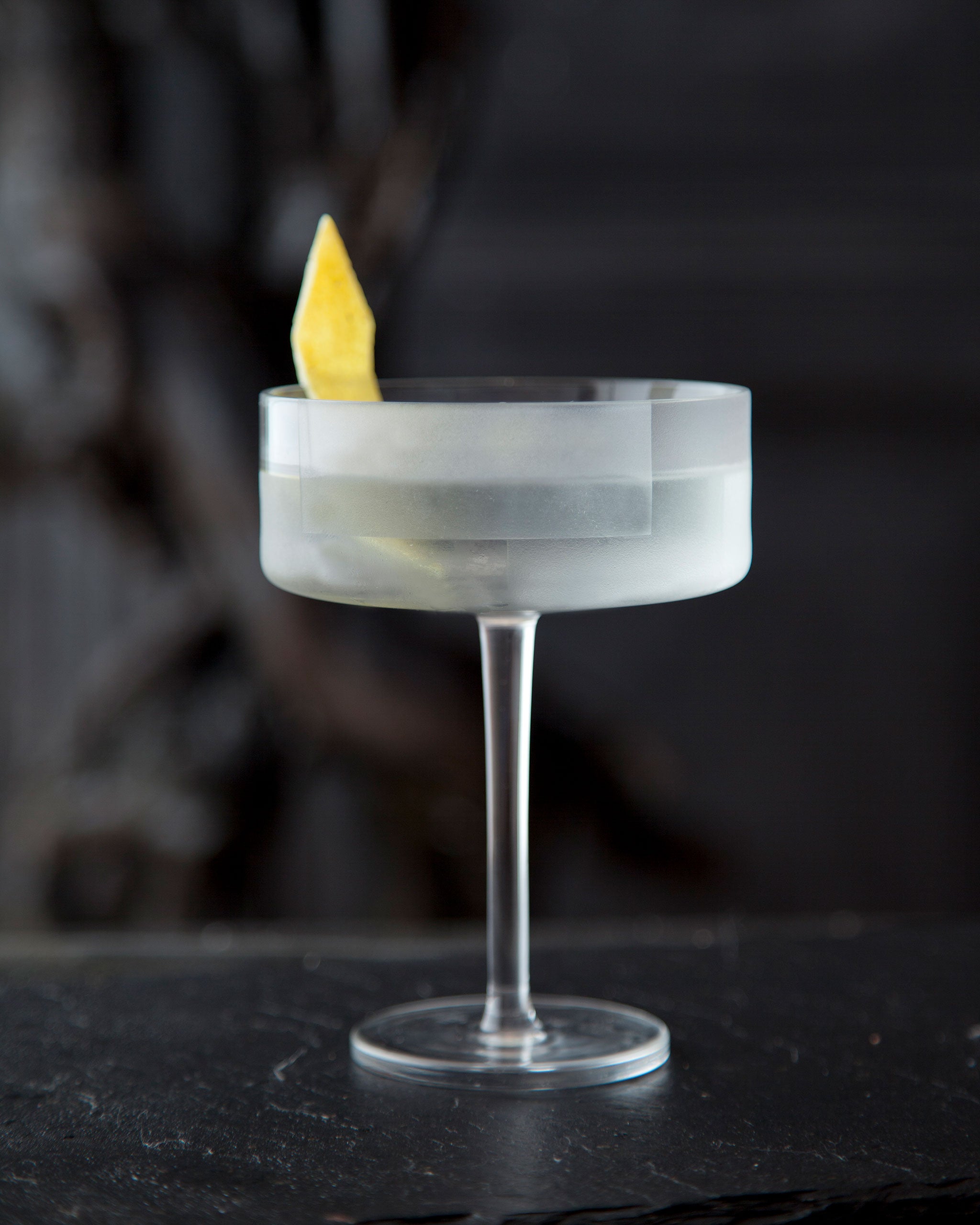 Crystal cocktail coupe with half-frosted geometric design with a lemon wedge on the rim.
