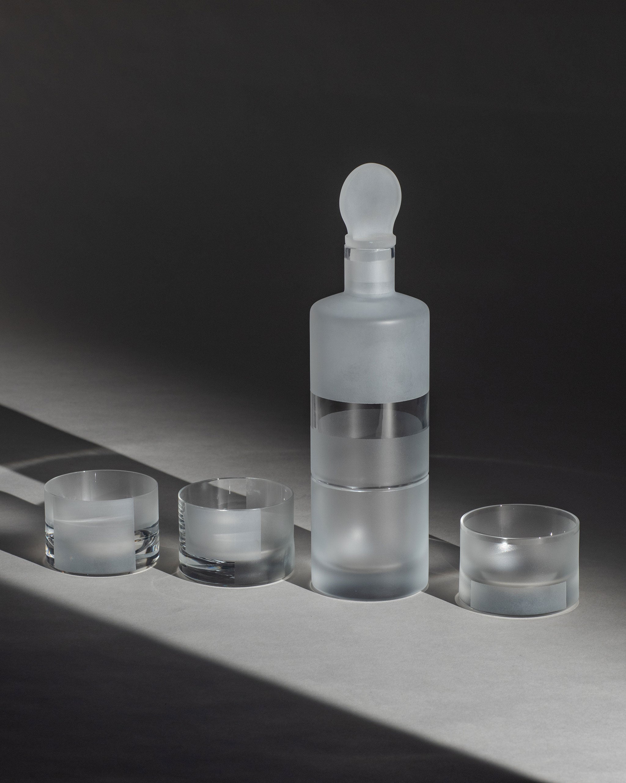 Modern crystal whiskey decanter with frosted band shown with matching whiskey glasses, elegant home bar set.