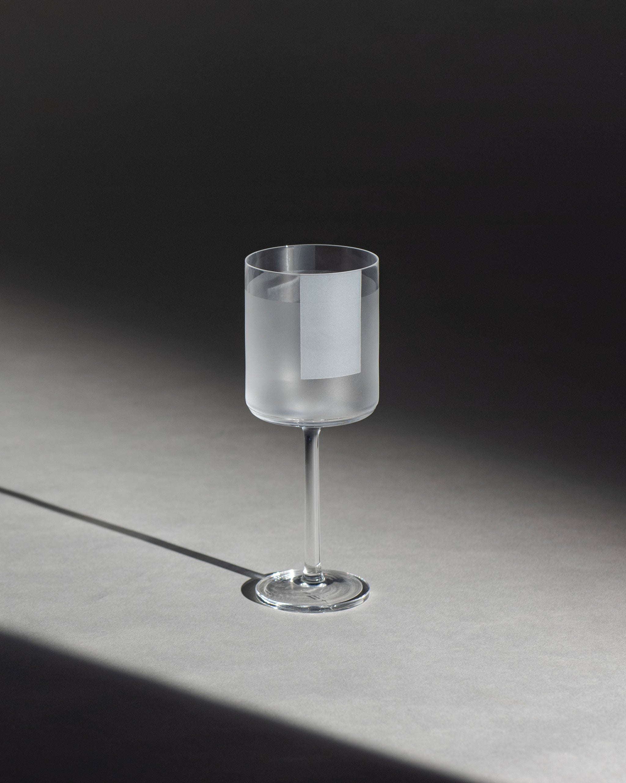 Delicate crystal white wine glass with half-frosted finish and geometric panels, perfect for serving chilled white wines against an ambient background