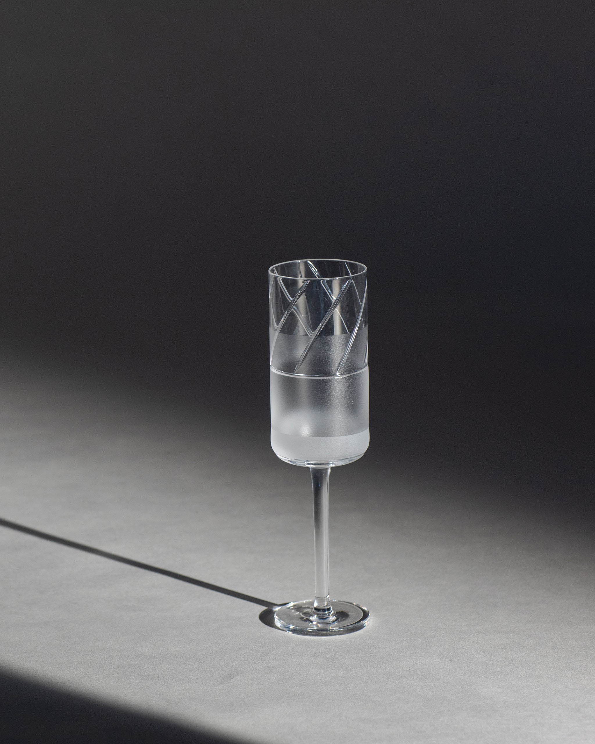 Tall crystal champagne flute with half-frosted geometric panels, ideal for celebrations or toasting occasions against an ambient background