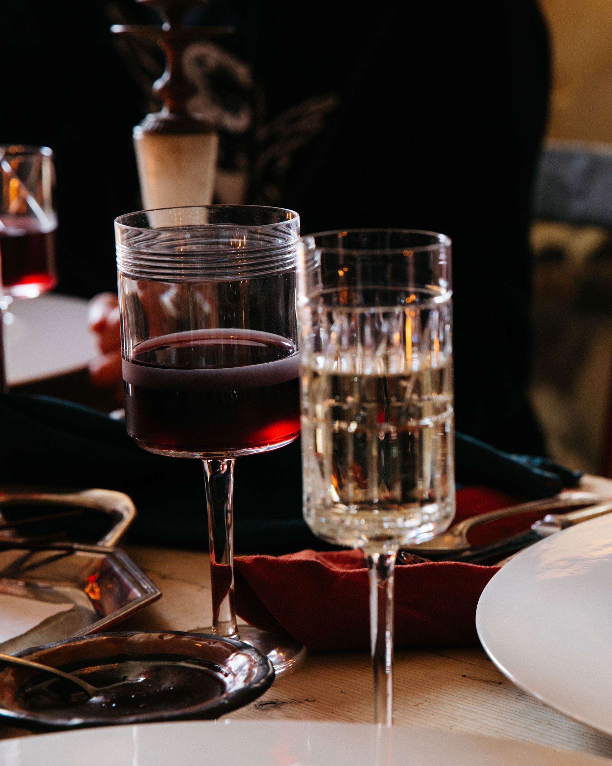 Red wine glass with cut crystal pattern and sandblasted panels on a festive dinner table with crystal glassware.