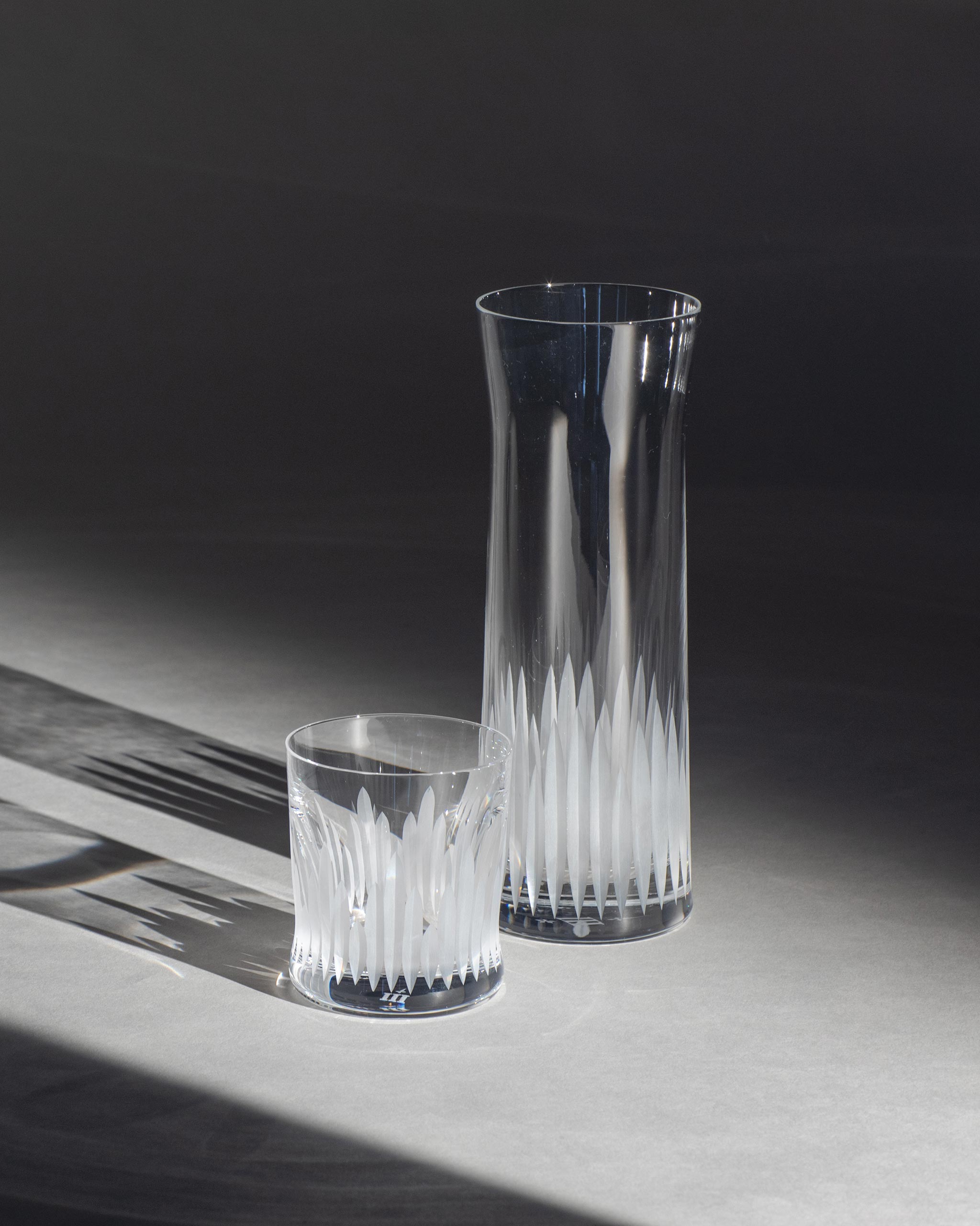 Unpolished hand-cut Irish crystal carafe and whiskey glass with deep angular cuts inspired by ploughed soil on an ambient background
