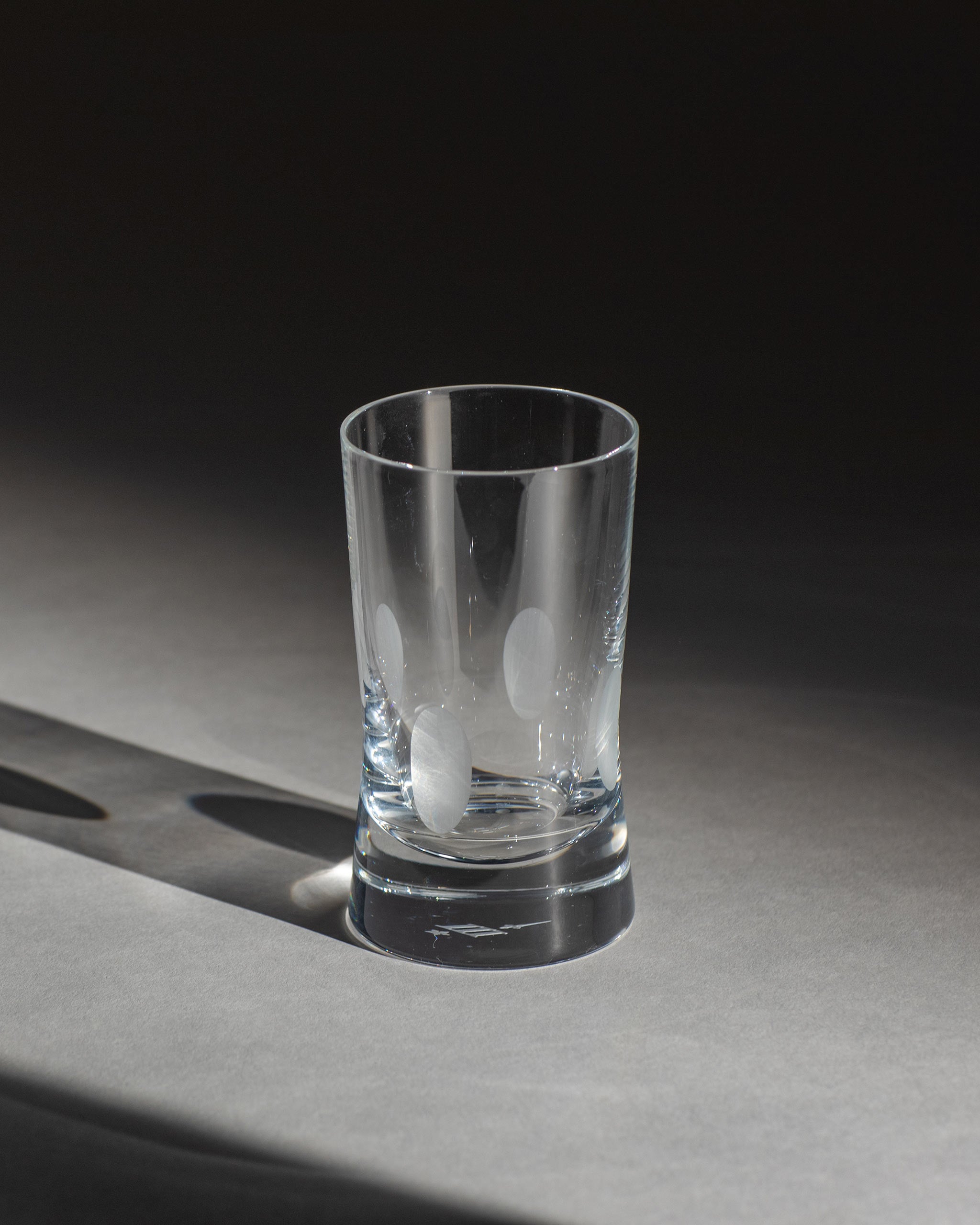 Unpolished hand-cut Irish crystal red wine glass with softly polished and sandblasted dew-cut detailing on an ambient background