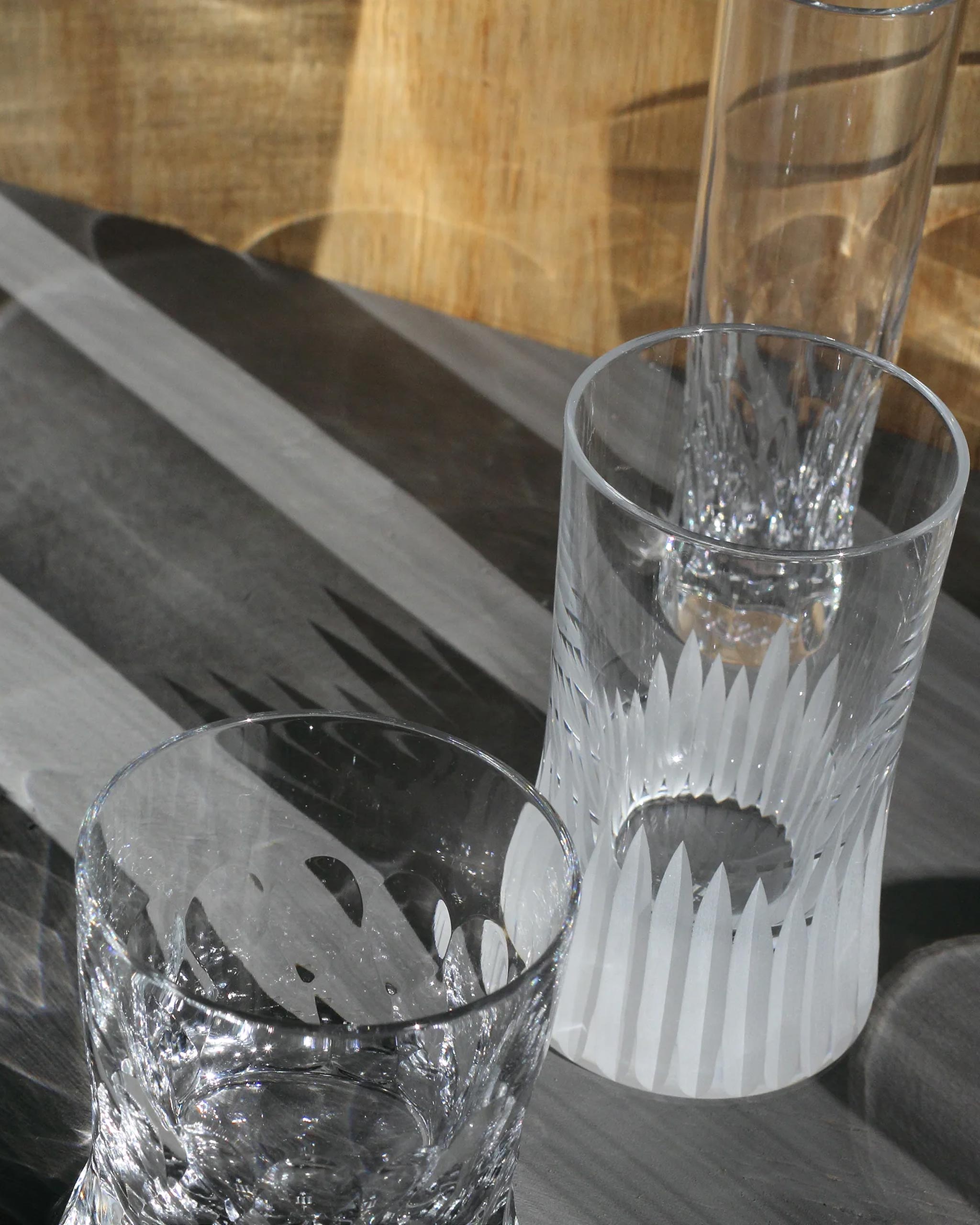 Trio of hand-cut Irish crystal glasses with deep angular cuts inspired by ploughed soil on an ambient background