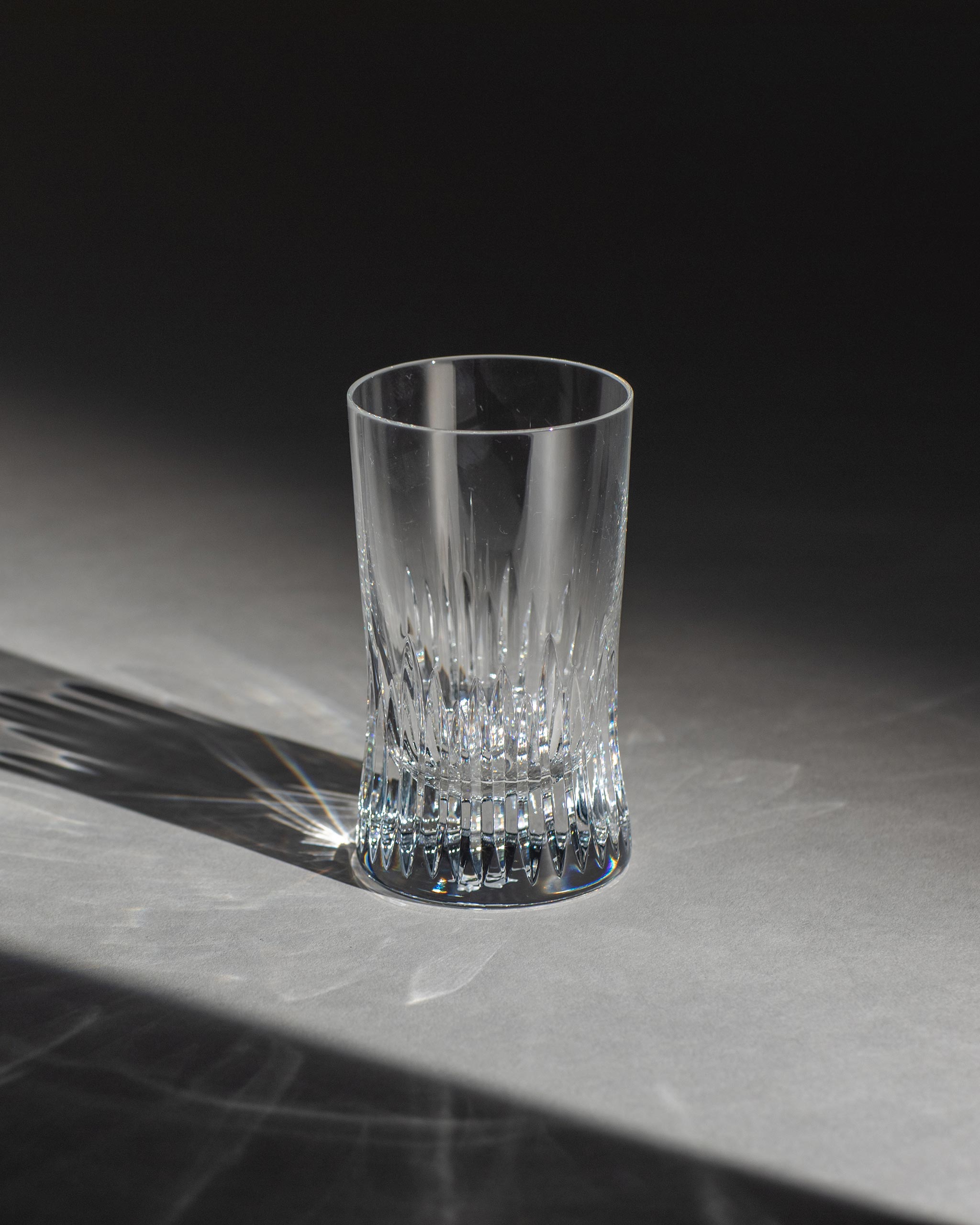 Polished hand-cut Irish crystal red wine glass with deep angular cuts inspired by ploughed soil on an ambient background