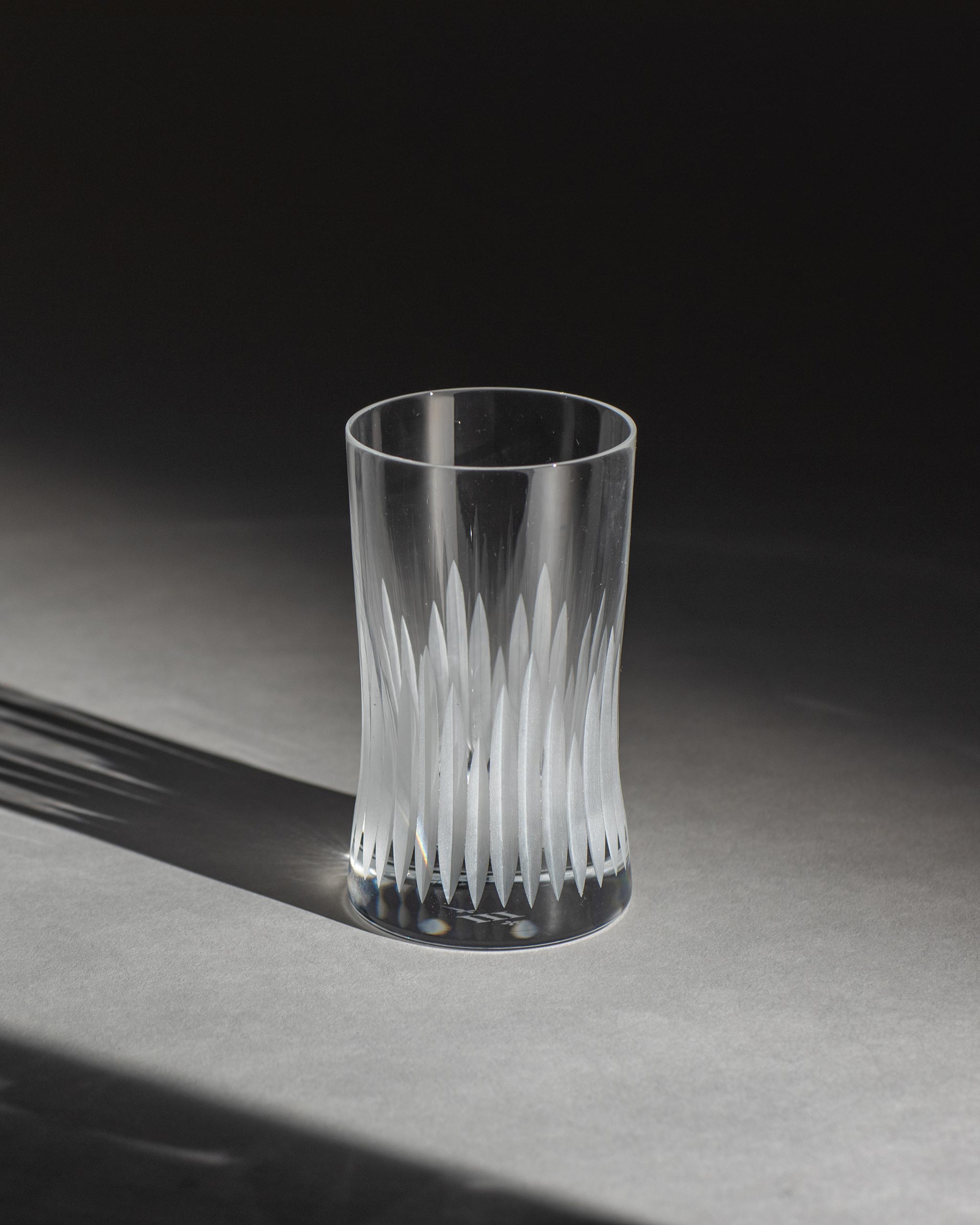 Unpolished hand-cut Irish crystal rocks tumbler glass with deep angular cuts inspired by ploughed soil on an ambient background