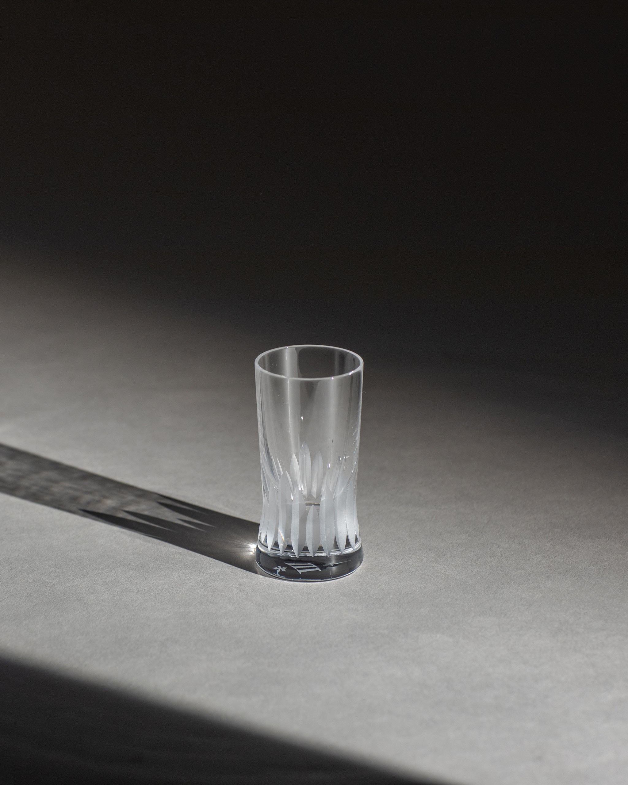 Unpolished hand-cut Irish crystal shot glass with deep angular cuts inspired by ploughed soil on an ambient background