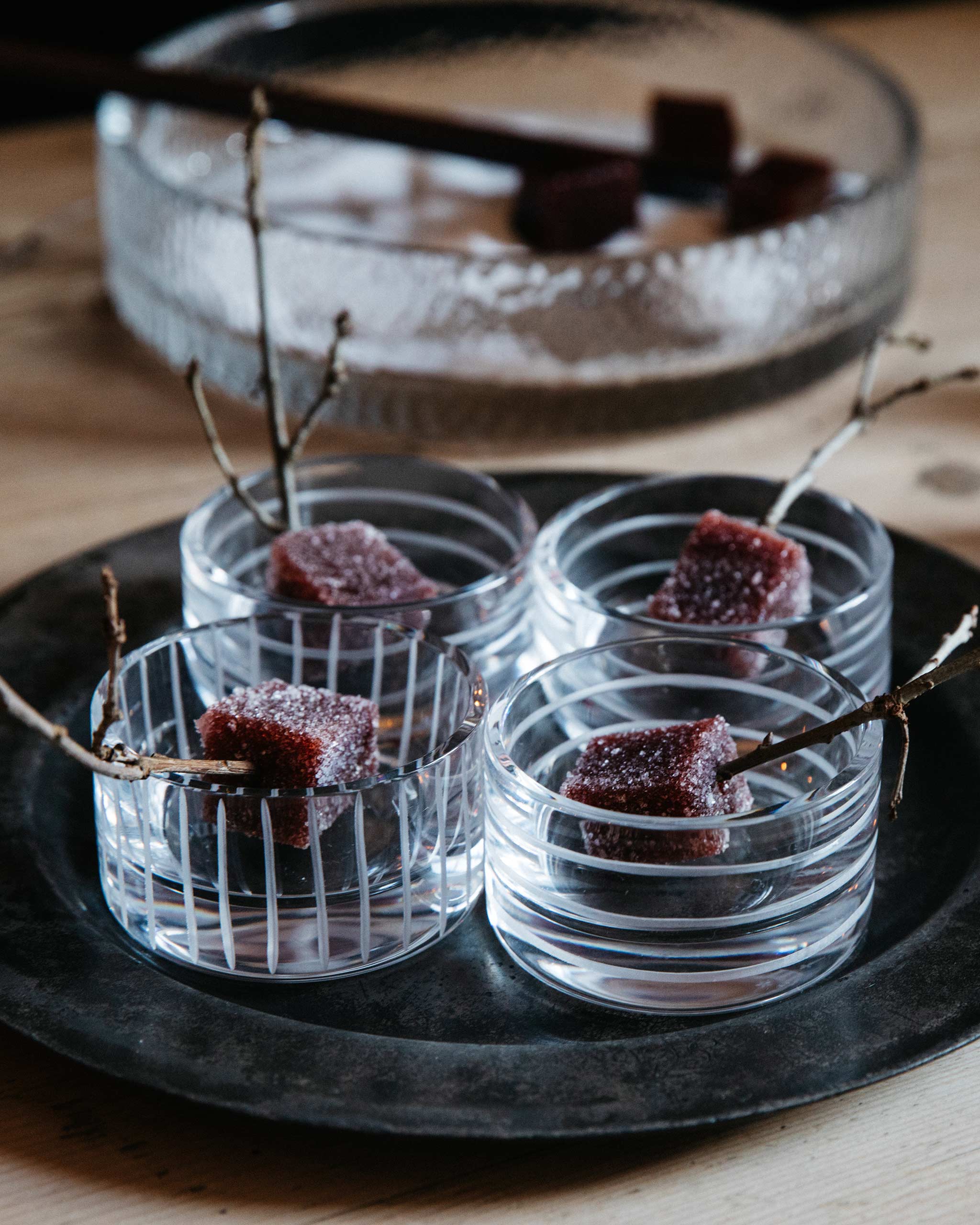 Loop crystal votive used as a serving vessel with Turkish delights and a decorative twig on a plate, a warm lifestyle scene blending craftsmanship and creativity.