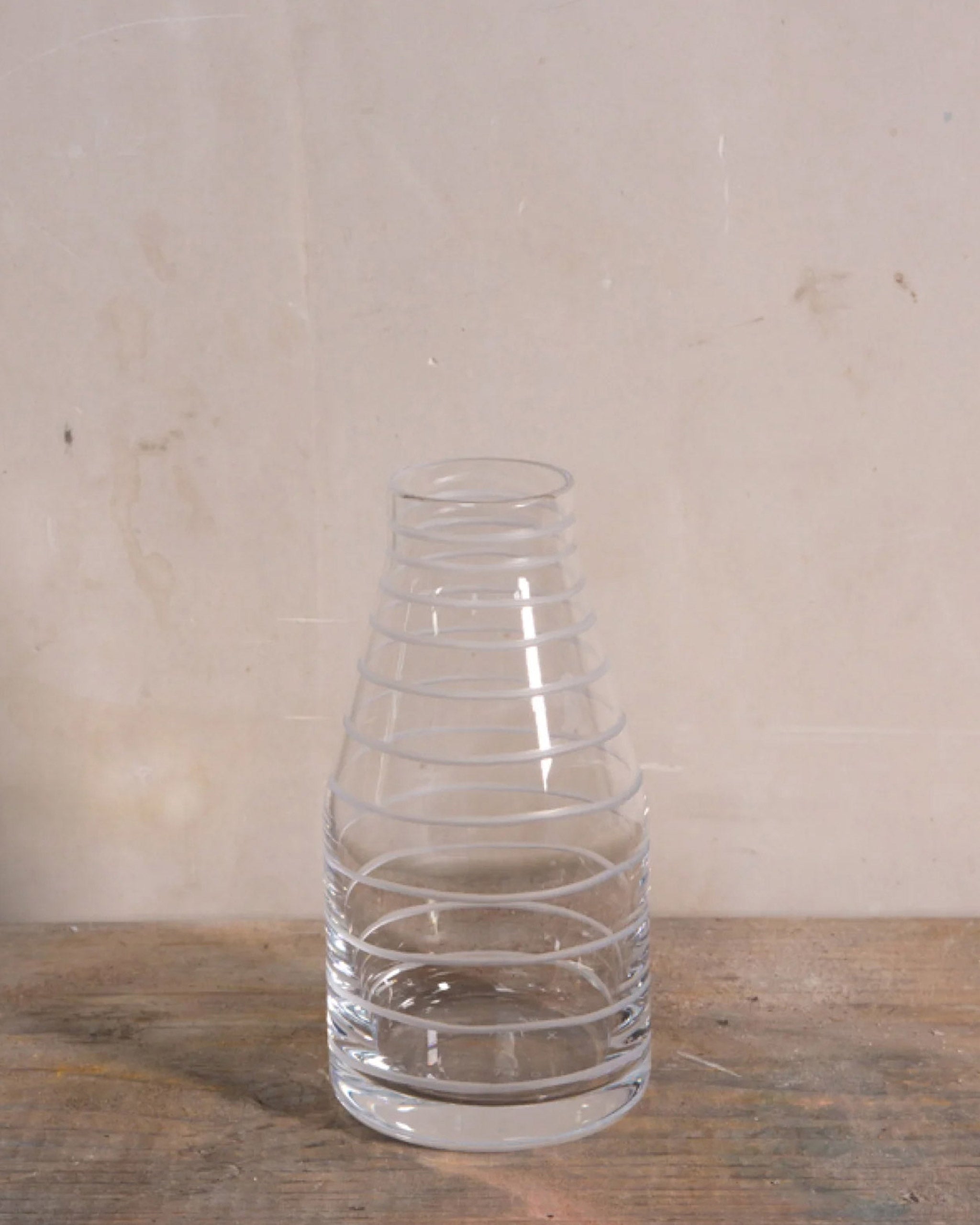Elegant hand-blown crystal carafe with continuous spiral detailing, inspired by the movement of water and thread, perfect for serving wine, sake, or water on a natural background