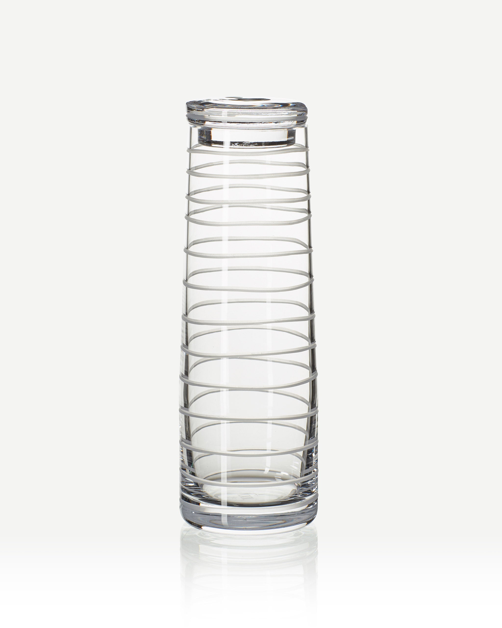 Handcrafted crystal decanter with a continuous loop pattern of horizontal cuts, echoing natural rhythm and movement, designed for sake, wine, or cocktails on a white background