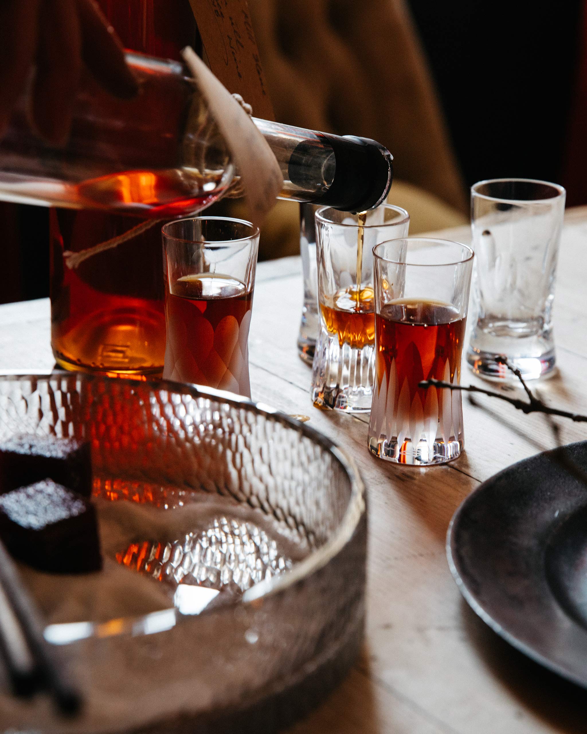Elegant bar scene featuring hand-cut crystal shot glasses in mixed designs, a bottle of whiskey and accompaniments 