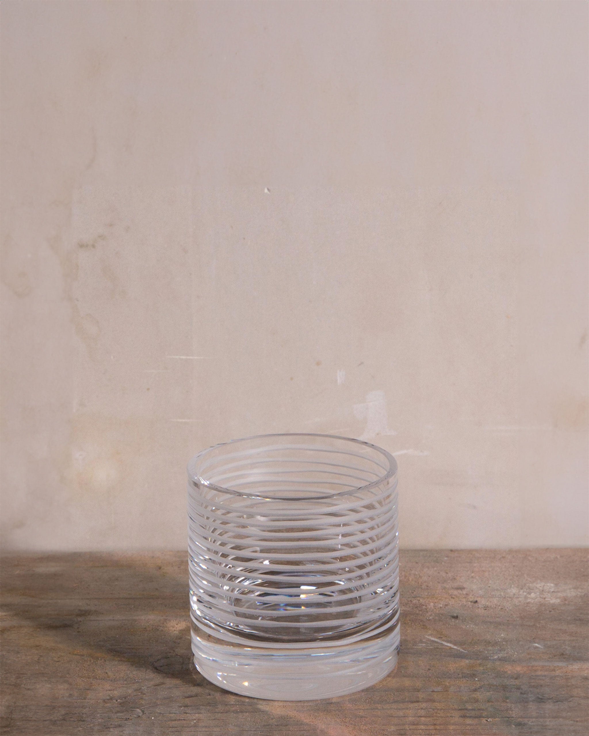 Hand-cut Irish crystal tumbler with continuous spiral cuts wrapping around the glass, inspired by ripples in water and rings in wood, ideal for whiskey, wine, or sake.