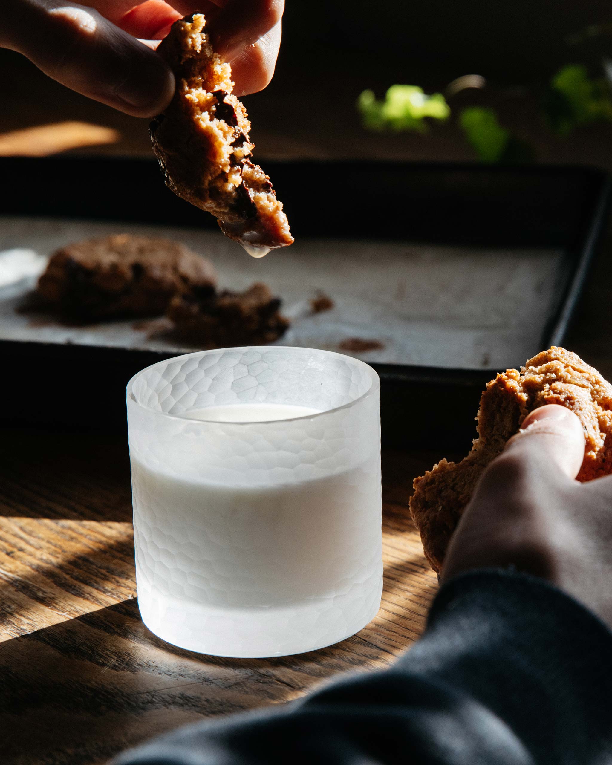 Hand-cut Irish crystal tumbler filled with milk, capturing a cookie being dunked, styled in a cozy, home setting.