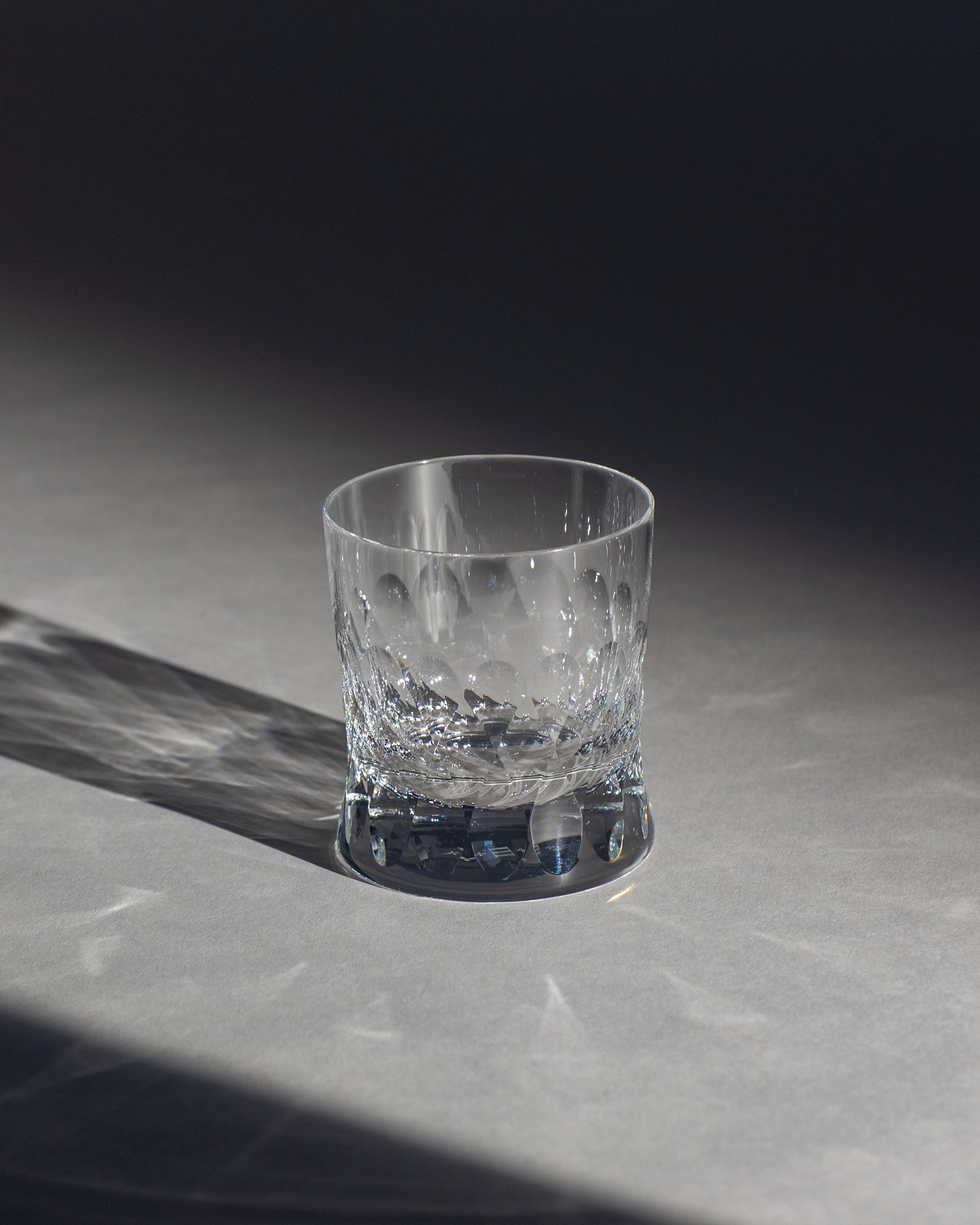 Polished Irish hand-blown crystal whiskey glass, with cut patterns on an ambient background