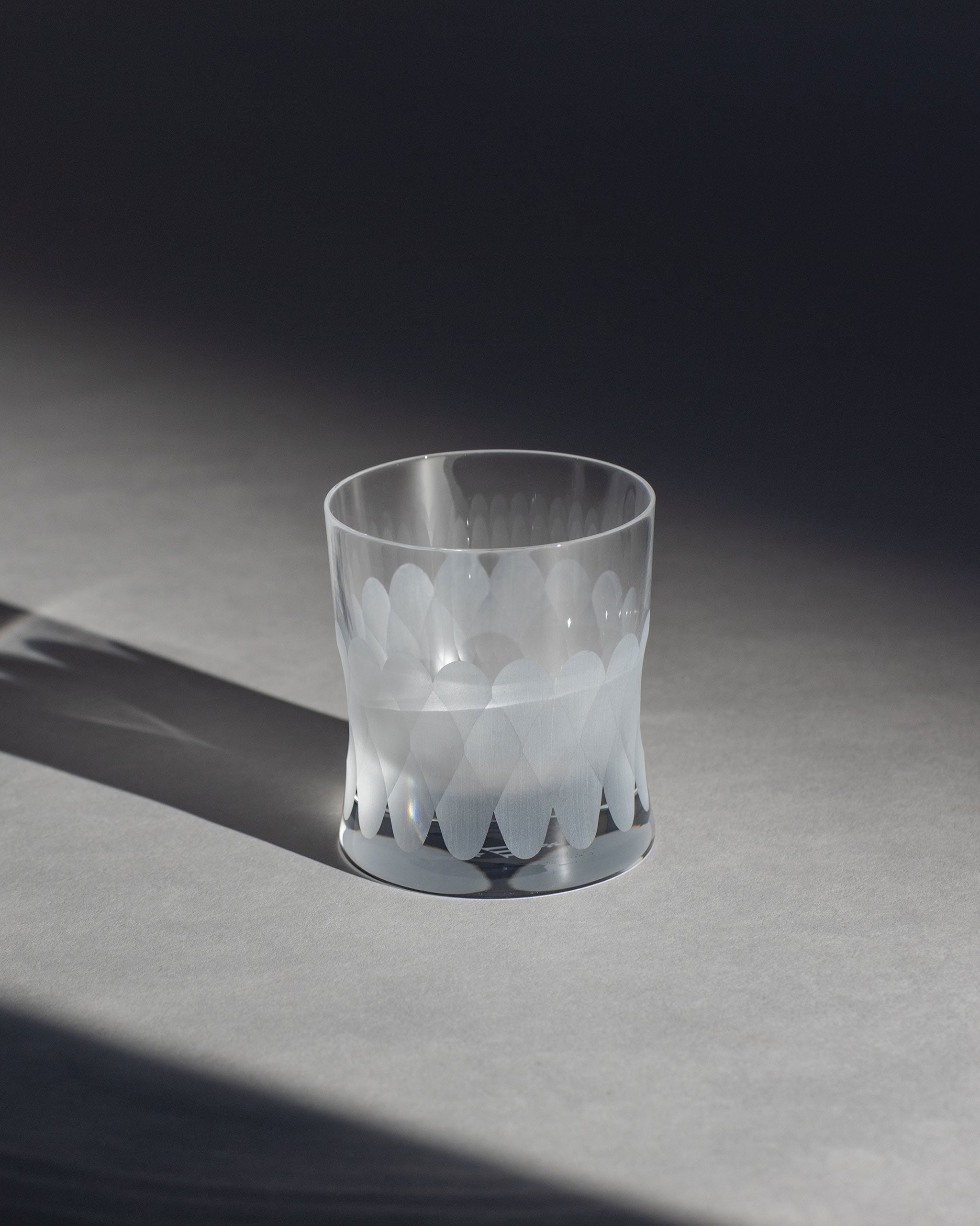 Unpolished Irish hand-blown crystal whiskey glass, with cut patterns on an ambient background