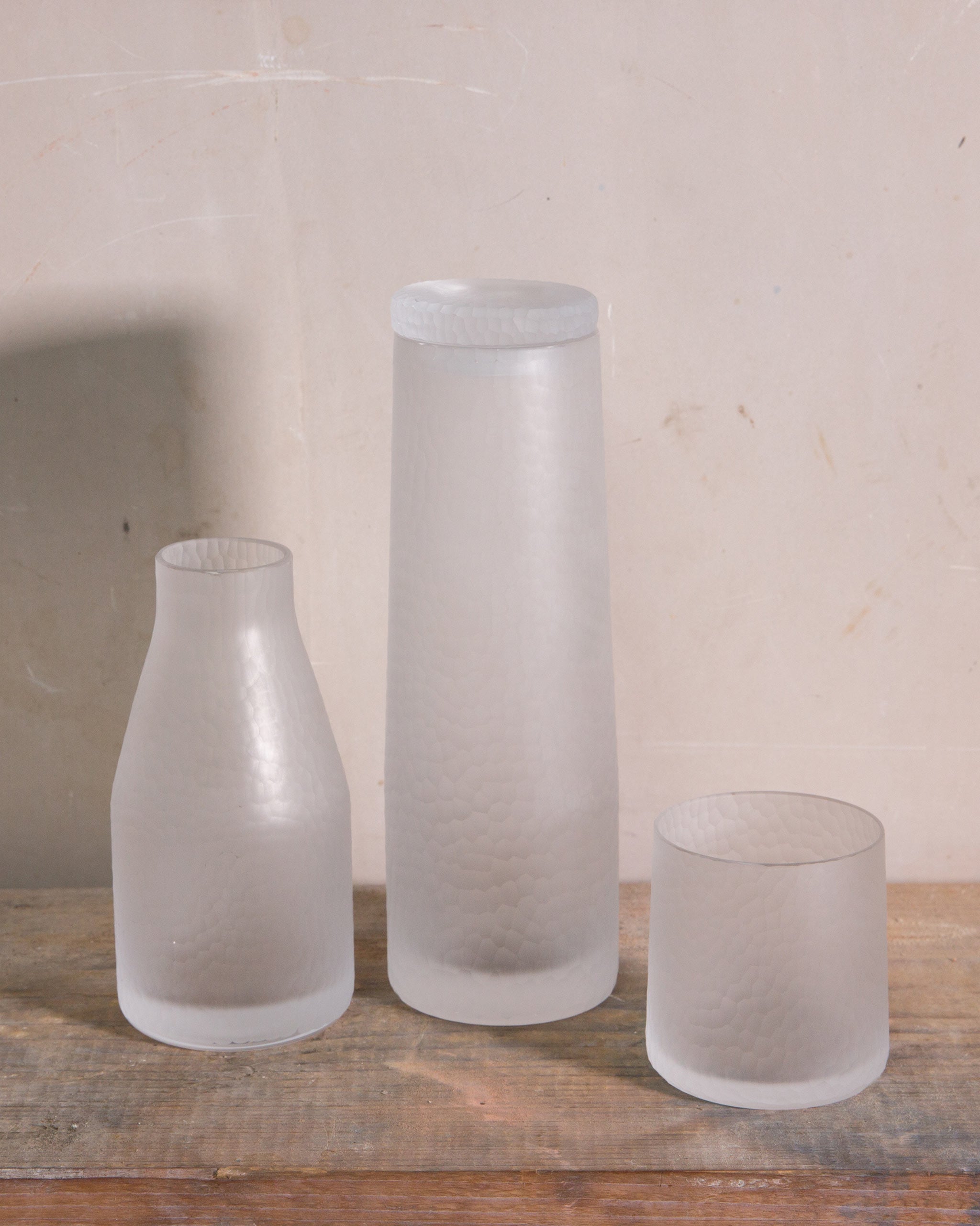 Over Collection hand-cut Irish crystal carafe, decanter, and tumbler displayed together on a natural wooden table, showcasing diffused textured surfaces and elegant forms.